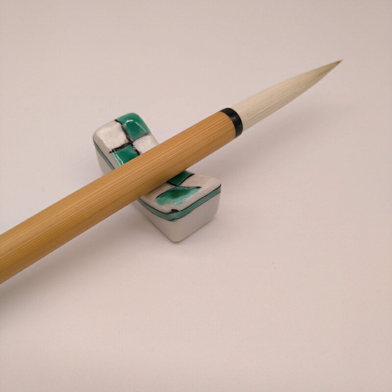 サイズ【商品サイズ】　15mm×35mm×高さ15mm素材陶器特徴九谷焼特有色鮮やかな発色の釉薬。 フと筆を休める時間も楽しくなります。注意※陶器製の特性上、商品サイズに若干の誤差ございます。 ※一点一点手作りの為、色柄に個体差ございます。 ※陶器製ですので割れ欠けにご注意下さい(割れ物です)商品名『陶器筆置市松柄(緑)1本置』【九谷×菊屋】九谷焼の筆置きです。※画像の筆は付属しておりません。フと筆を休める時間も楽しくなります。※画像の筆は付属しておりません。九谷焼特有の鮮やかな色彩趣味の世界に彩りを。