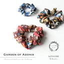 WINSOME Liberty ウィンサムリバティ Garden Of Adonis ガーデン・オブ・アドニス リバティ タナローン コットン シュシュ リバティプリント merge オリジナル シュシュ 32WSL-CHOU-GARDENOFADONIS 豊富な絵柄からシュシュに最適な選りすぐりの柄で。 リバティプリントとは、イギリス・ロンドンの老舗百貨店であるリバティ百貨店のプリント生地のこと。19世紀後半より続く長い歴史の中で生まれた数々の図案はもちろん、 新鋭デザイナーにより生み出される柄や復刻柄など、年2回発表されるコレクションには、いつもワクワクせずにはいられません。 リバティプリントは、シーズンコレクションと言われる季節限定の柄とエターナルコレクションという定番柄の大きく2つのコレクションに分かれます。エターナルコレクションは安定的に生産されるとはいえ、毎年コレクションの見直しがあるため、エターナル柄でも廃盤になってしまうものもあり、永久にその柄が存在し続けるということではないようです。エターナル柄は人気柄ほど色展開が豊富で、色によって雰囲気がまるで違って見えるのも特徴で、だからこそ柄と色のバランス感を大切に、目を惹くけれど決して派手過ぎず、着けるだけでセンスの良さがにじみ出るような絵柄を選んでいます。 Garden Of Adonis ガーデン・オブ・アドニス ギリシャ神話に登場する女神アフロディーテの不死の恋人、アドニスの祭りを表現したデザイン。リバティアーカイブのデザインをベースに、アドニスの象徴であるアネモネ、マリーゴールド、ペチュニア、シャクヤクなどの様式化された植物が花瓶にレイアウトされ、茎がうねるようなデザインが動きとダイナミズムを表現しています。 ●BRW ｜赤味強めの弁柄色のようなブラウンベース。暖色系でまとめられたリバティには珍しい色味。 ●BLK ｜ほのかに赤味の混ざった黒ベースにオレンジや黄色の絵柄。 ●BLUE ｜落ち着いたネイビーベースに青系の同系でまとめられた配色。 アフリカのタナ湖近くで取れる長綿花が原料。 リバティプリントにはさまざまな生地がありますが、中でも代表する素材が「タナローン」と言われるコットン生地です。リバティのタナローンは、横糸に100番手、縦糸には70番手というとても細い糸で織られていて、その昔シルクが高騰した時にシルクの代用品としてリバティロンドン社が独自に開発した素材です。アフリカのタナ湖近くでとれる長綿花が原料であることが素材名の由来で、極細糸で織られた高密度なキメ細やかさと、シルクのような光沢、薄手でしなやかでシワになりにくい、欠点が無いほどの完璧な生地なのです。 ミニとセミレギュラー、サイズは2種類。 ●ミニ｜当店オリジナルのEMILIO PUCCIシルクシュシュのミニサイズと同じサイズ感です。着けるシーンや髪の長さを選ばず、フェミニンになり過ぎないコンパクトなサイズは、気負いせずに着けられて年齢を問わずお使いいただけます。生地幅は細く、けれど生地の長さはたっぷり使っているので、細かくギャザーが入ってクシュクシュっとした感じが可愛い雰囲気です。エミリオプッチのシルクシュシュと異なるのは、コットン素材なので洗えること。より身近に普段使いしたいリバティプリントのシュシュです。 ●セミレギュラー｜シュシュはしっかりとギャザーが入って立体感のある感じが可愛いと思うので、生地幅はコンパクトながら、ギャザーをクシュクシュと入れるため生地の長さを贅沢に使っています。かと言って、大きすぎるシュシュは髪の長さを選ぶので、髪の長さを選ばずに使いやすいサイズ感と可愛さにこだわって作りました。ほどよい華やかさが楽しめるセミレギュラーサイズです。 髪や手首に手軽に華を添える。 これひとつでたちまちヘアアレンジが完成する便利なシュシュは、OLさんから子育て奮闘中のママまで、凝ったヘアスタイルが出来ない忙しい女性たちの「手間を掛けずにオシャレしたい！」という気持ちに応えてくれます。 贈り物には別売りのギフトボックスを。 まるでお菓子みたいなラッピングが可愛い透明のギフトボックスと、高級感たっぷりでちょっと大人な雰囲気のマットブラックの紙箱をご用意しています。贈り物としてご利用いただく際はぜひ一緒にご注文ください。ギフトボックスは別売りで宅配便でのお届けとなります。 ※画像をクリックするとギフトボックスのページへジャンプします。