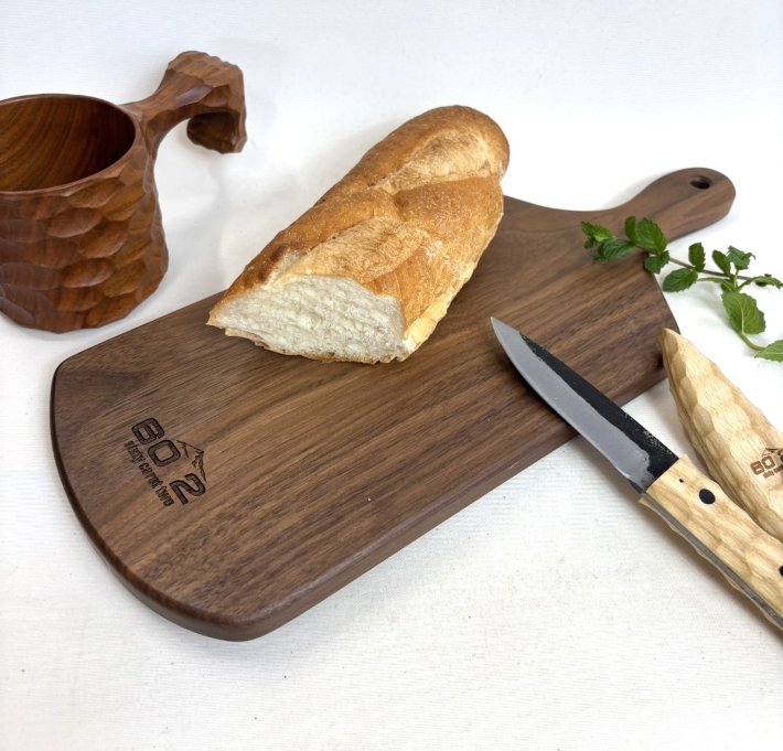 サイズ 38cm×15cm×厚み1.5cm 材料 ウォールナット 塗装 自然オイル塗装 ご注意 天然の木をそのまま使用していますので、木目、色合い等は商品ごとに異なります。 　ご理解いただきまして、ご注文をお願いします。 納期目安 ご注文確認後、3～4営業日 送料ランク 送料無料 梱包サイズ、個数 1個ウォールナット製のカッティングボード　サイズ：38×15×厚み1.5cm持ち手の付いた便利でおしゃれなカッティングボード。お料理をのせてそのまま食卓にもOK。アウトドアにも活躍。 伊川彫刻店オリジナルブランド「sixty carat two」のロゴマーク入り こちらのカッティングボードは、樹種とデザイン違いが全3種類あります。 ・ヒノキA ・ヒノキB ・ウォールナット（当ページの商品です）