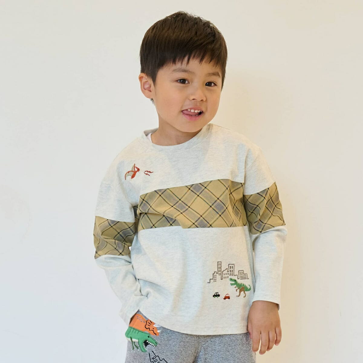 [型番：5353224]大胆なチェック柄の切り替えデザインが目を引くTシャツです。恐竜が街中に現れた、ユニークな刺しゅうに心惹かれます。バックネックにあしらった織りネームもポイント。肌当たりの良いコットン100％生地のため、一枚で快適な着心地です。内側にお名前を記入できるタグがついています。※80、90サイズのみ肩開き【透け感】透けない【生地の厚さ】普通【伸縮性】あり【裏地】なし【ポケット】なしカーキ：モデル身長：93cm 着用サイズ：90cm シロ杢：モデル身長：110cm 着用サイズ：110cm ■カラー：シロ杢、カーキサイズ：着丈×胸囲×肩巾×袖丈90cm：35.5×66×31×26.5100cm：39×70×33×30.5110cm：43×74×35×34.5120cm：47×78×37×38.5130cm：51×82×39×42.5※(　)で表記されている数字はヌードサイズです。ヌードサイズとは衣服を身につけない身体のサイズです。お客様ご自身の身体サイズと比較してお選びください。 ■素材： 本体：綿100%別布：綿80%別布：ポリエステル20% ■お手入： 洗濯方法は商品タグをご確認ください&nbsp;&nbsp;>>商品のお取り扱い方法 ■原産国： 中国恐竜と街チェック切替長袖Tシャツ／クレードスコープ（kladskap）シロ杢カーキ画面上と実物では、多少色具合が異なって見える場合がございます。