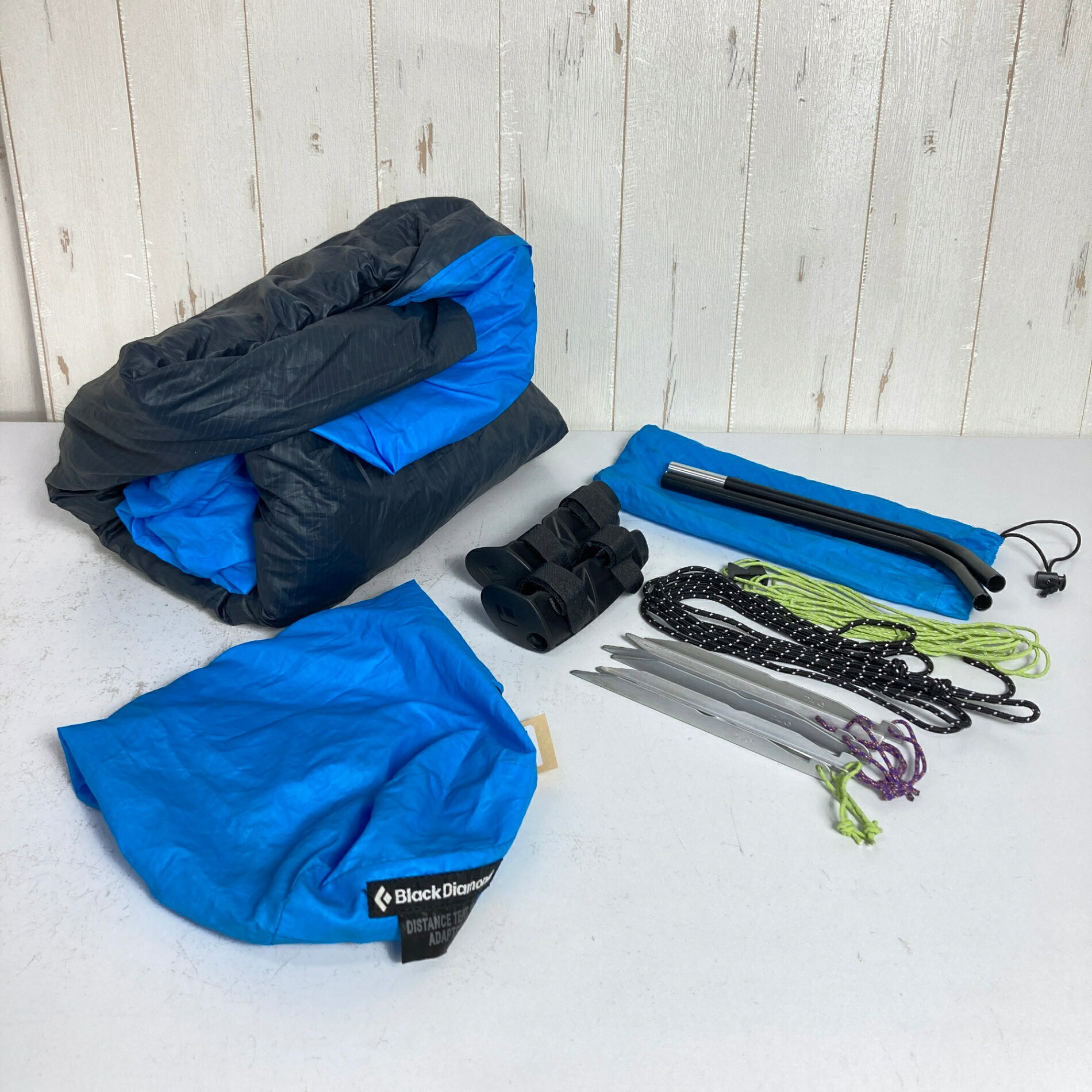 【OneSize】【 OneSize ブルー系】Black Diamond ( ブラックダイヤモンド ) ディスタンス テント W アダプター Distance Tent W Adapter ポリエステル キャンピングギア テント 山岳テント z00060037 ブルー系 キャンピングギア テント 山岳テント ・セカンドギア在庫コード: IT8TJCSR71ZX（お問い合わせの際はこちらをお伝え下さい） ・メーカー: Black Diamond ( ブラックダイヤモンド ) ■素材情報 ・組成: ポリエステル100% ■サイズ情報 ・代表サイズ: OneSize ■カラー ・カラー系統: ブルー系 ■コンディション ・グレード: 中古D ※グレーディング目安　 ├ 新品：当店オリジナル製品 ├ 未使用：新古品 ├ 中古S：新品同様 ├ 中古A：美中古 ├ 中古B：良い状態の中古 ├ 中古C：通常使用可能な中古 └ 中古D：通常使用困難な中古 ・コンディション詳細・備考: ■状態スコア：31 / 100 点 ■状態明細：旧モデル / 【II】経年考慮 / 顕著な経年劣化（シームテープハガレ / 生地の劣化によるしっとり感 / PUの浮き） / 若干の使用感 / 若干の汚れ（入口下部） / 若干のスレ（各所） ■採寸値・実測値 ※全て外寸値です。また、手作業による採寸および簡易な秤による計測のため、誤差はご容赦下さい。 ・総重量（付属品等含む）: 920g ■カタログスペック ※以下はメーカー公表のスペック値をそのままにご紹介するものです。表現・仕様・付属物の有無等、お品物現品との完全な一致をお約束するものではございません。 トレッキングポールをフレームの一部として利用することで、大幅な軽量化を実現した2人用シングルウォールテントです。荷物をできるだけ軽くしたいファストパッキングや長距離縦走、ULスタイルのテント泊に適しています。 付属のアダプターを使用し、2本のトレッキングポールとDAC製クロスポールを接続して設営する独自構造を採用。一般的なトレッキングポールを活用できるため、専用の長いテントポールを携行する必要がなく、装備全体の軽量化とコンパクト化に貢献します。 本体には軽量な30デニールのポリエステル生地を使用。天頂部と足元にはベンチレーションが設けられ、シングルウォール構造でありながら内部の換気にも配慮されています。4か所のステークアウトポイントを備え、素早く確実に設営できるのも特徴です。 本体重量はトレッキングポールを除いて約725g、収納サイズは約13×30cm。重量を抑えながら、就寝人数2人分のスペースを確保した軽量シェルターです。 ※設営にはトレッキングポール2本が必要です。トレッキングポールは付属しません。