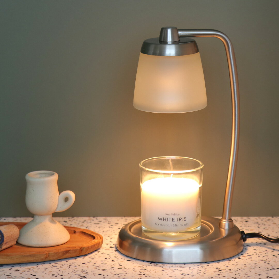 Contempo CANDLE WARMER LAMP 火を使わずキャンドルの香りを楽しむキャンドルウォーマーライト。 使い方はとっても簡単。お気に入りの香りのキャンドルをセットしてスイッチを入れるだけ。 優しく灯るライトの灯りとアロマキャンドルの香りでリラックスタイムをお楽しみいただけます。 火を点さなくてもいいので、ライターやマッチを準備したり煙や煤が出ないので手軽に使うことができるのも嬉しいところ。 ベッドサイドなどのようなキャンドルを灯すのに気をつけて使う場所でも安心してご使用いただけます。 ランプでキャンドルを温めることで火を灯すよりもキャンドルが多く溶けるため、香りも広がりやすくお部屋をお気に入りの香りで満たしてくれます。 また、火を灯すとキャンドルが気化して減っていきますが、ライトで温めると気化すること無く冷めるとまた固まるのでお気に入りのキャンドルを永く使うことができます。 ウォーマーには本体にセットされている専用ハロゲン電球のほかに、さらに1個交換用電球が付属。 商品名 コンテンポキャンドルウォーマーランプ 色 ブラック/シルバー サイズ 本体サイズ：W132×L158×H275mm コードの長さ：約1.5m　中間スイッチ付き 重量(g) 785(g) 仕様 定格電圧：100V　適用電灯の定格消費電力：25W　専用ハロゲン電球2個付き 使用可能な適切なサイズの範囲：直径約90mm×高さ約65～85mm &#9654;アロマ 一覧を表示