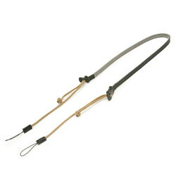 Flynn Camera Strap／フリン カメラストラップ（本製品）はアルティザン・アンド・アーティストがアメリカ人写真ジャーナリスト、ショーン・フリンのカメラに使用されていた、パラコードのストラップに感銘を受け開発したストラップ。耐荷重に優れた素材パラコードとレザーのコンビネーションが魅力のストラップには、アルティザン・アンド・アーティストならではの美しさと機能性が備わっている。左右双方で長さ調整ができることに加え、片側にはカメラの着脱が簡単にできるバックルを採用。パラコードの先端部分は自然にほどけることがなく、長さ調整時につまみやすい「セルティックボタンノット」を職人が一本一本、丁寧に結んでいる。コンパクトカメラでの使用を想定した本モデルには新たに開発した“松葉紐接続”を採用、パラコードと松葉紐の接続部は熟練の職人により丁寧に縫製・補強されており、十分な耐久性を確保している。耐荷重に優れたパラシュートコード*とレザーを組み合わせた新ジャンルのストラップ。パラコードの先端部分には一点一点手作業でセルティックノットという結びが施され、見た目の楽しさに加え、つまみやすいデザインに。ノットをつまんで左右の長さを別ーに調整できる仕組みになっており、ハイエンドなコンパクトカメラをアクティブに操ることを可能にする。また片側の調整パーツバックルになっているのでカメラの着脱がスムーズ。レザー部分は、表面にスムースレザー、裏面に肌触りの良いベロアを重ねた仕様で適度な厚みがあり、快適な着用感を実現。カラーはレッドとネイビー、そしてミリタリーテイストを感じさせるタンの3色。グランピングやアクティブなアウトドアシーン、また街中でのスポーティーなスタイリングで活躍するストラップです。 *パラシュートコード：パラシュートに使用されているナイロン製の強靭なコード。汎用性が高く、アウトドア・シーンに限らず様々なシチュエーションで重宝されているストラップ部幅12mm長さ700～1300mm質量23g対応カメラ松葉紐接続のコンパクトカメラ材質・素材牛革・ナイロンフリンさながらのアクティブな精神をもつ人たちへ 「フリン カメラストラップ」
