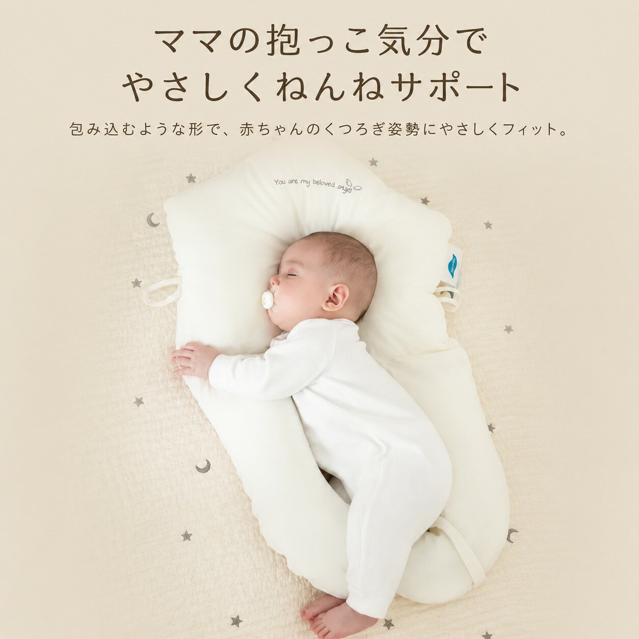 商品説明 赤ちゃんのくつろぎ時間やねんね前のリラックスタイムに寄り添う、抱っこサポートピローです。 頭まわりから体の両サイド、脚まわりまでやさしく包み込むようなU字型設計で、赤ちゃんが落ち着きやすい姿勢をサポートします。 側地には肌ざわりのよい綿100％素材を使用。 赤ちゃんの肌にふれるものだから、やわらかさと清潔に使いやすい仕様にこだわりました。 左右のひもを引くだけで枕幅の調整ができ、赤ちゃんの頭幅や体格に合わせてフィット感を調整できます。 成長に合わせて使いやすいベビー用サポートクッションです。 商品の特徴 1. 包み込むようなU字型設計 頭まわりから脚まわりまで、赤ちゃんの体に沿うようにやさしくフィット。 ママに抱っこされているような安心感のある使い心地を目指しました。 2. 頭まわりをやさしく支える中央ヘッドサポート 中央部分は赤ちゃんの頭をやさしく受け止めるくぼみ形状。 ふんわりとしたクッション性で、ねんね時のくつろぎ姿勢をサポートします。 ※本商品は医療機器ではありません。頭の形を矯正するものではありません。 3. 左右のひもで枕幅を調整 赤ちゃんの成長や体格に合わせて、左右のひもで枕幅を調整できます。 きつく締めすぎず、赤ちゃんの様子に合わせてやさしく調整してください。 4. 腕を置きやすい立体クッション 両サイドのクッション部分は、赤ちゃんの腕を自然に置きやすい立体形状。 体の横にやさしく寄り添い、落ち着いた姿勢をサポートします。 5. 脚まわりまでやさしく包み込む 下部のクッションが脚まわりに寄り添い、赤ちゃんの体をやさしく包み込みます。 寝返り前のくつろぎ時間や、保護者の見守り中の休憩スペースにもおすすめです。 6. 綿100％側地でやさしい肌ざわり 側地には綿100％素材を使用。 赤ちゃんの肌にふれるものだから、やわらかくナチュラルな質感に仕上げました。 7. 丸洗いOKで清潔に使いやすい 汚れが気になる時は丸洗いできるため、毎日使いやすい仕様です。 洗濯後は形を整えて、風通しのよい場所でしっかり乾かしてください。 ※洗濯の際は洗濯表示をご確認ください。 ※洗濯ネットの使用をおすすめします。 こんな方におすすめ 赤ちゃんのねんね時間をやさしくサポートしたい方 抱っこされているような安心感のあるクッションを探している方 新生児から使いやすいベビー枕を探している方 丸洗いできるベビー寝具を探している方 出産祝い・ベビーギフトを探している方 シンプルでやさしいデザインのベビー用品を探している方 商品仕様 商品名：抱っこサポートピロー サイズ：約72×45×8cm 重量：約460g 側地：綿100％ 中材：ポリエステル繊維、PEソフトパイプ 対象年齢目安：0〜24ヶ月 カラー：ホワイト系 お手入れ：丸洗い可能 ※手作業採寸のため、若干の誤差が生じる場合があります。 ※入荷時期により、細部の仕様が若干異なる場合がございます。 使用上の注意 必ず保護者の目の届く範囲でご使用ください。 赤ちゃんの顔や口元をふさがないよう、使用中は姿勢をこまめにご確認ください。 長時間の連続使用や、保護者の見守りがない状態での使用はお控えください。