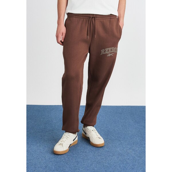 リーボック メンズ カジュアルパンツ ボトムス VARSITY ARCH JOGGER PANTS - Tracksuit bottoms - campus brown