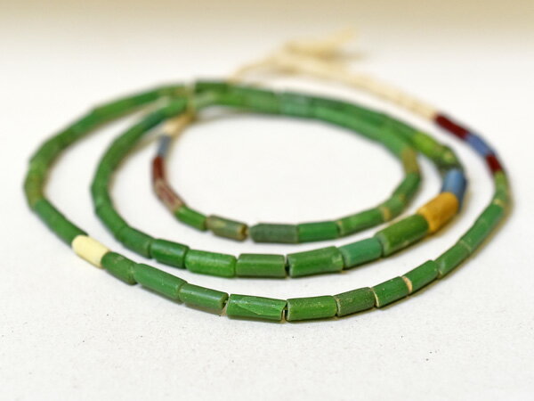 西アフリカ、マリ共和国の北部ジェンネ周辺で発掘された、丸管型緑色のビーズを中心とした希少形状のニラビーズ（ローマンビーズ）一連です。1～4世紀ごろに交易品として、古代ローマ帝国領からこの地にもたらされたと思われるビーズです。色は緑がメインで、水色、紫、黄色等が数個混じっいます。現在では、発掘量が少なくなり、流通量も減ってきています。3～4粒に若干の欠等の小傷がありますが、状態は概ね良好な希少な一本です。 ■商品詳細■ 全長：約60cm(ビーズ部分のみ) 粒のサイズ(長さX直径)：8.5X3.0mm(最小)～11.0X5.0mm(最大) 孔径：0.8～1.0mm 材質：ガラス 推測原産地：地中海沿岸地域 推測製作年代：1～4世紀 蜻蛉玉,トンボ玉,とんぼ玉販売,アンティークビーズ販売希少形状!【2411】マリ出土 古代ローマン丸管型ニラビーズ一連3