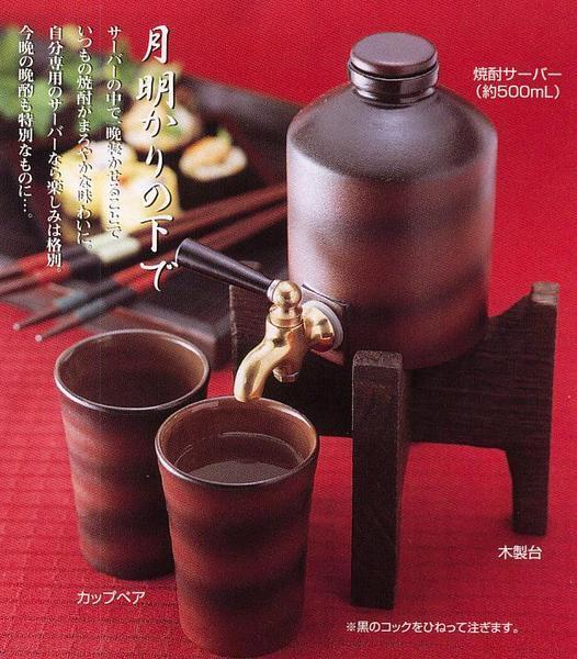 日本酒＆焼酎サーバー 陶器製カップ2個付き！ 　サーバーの中で一晩寝かせることで いつもの焼酎がまろやかな味わいに。 自分専用のサーバーなら楽しみは格別。 今晩の晩酌も特別なものに・・・。 　焼酎を飲んだ分だけつぎ足すことにより、常に熟成させ、味わいの深い、まろやかな焼酎をご堪能いただけます ◆商品詳細　　　　　　　　　　　 焼酎サーバー約500ml（140×Ф85mm・陶器・真鍮） カップ×2ヶ（95×Ф70mm・陶器） 木製台（高さ100mm・天然木）