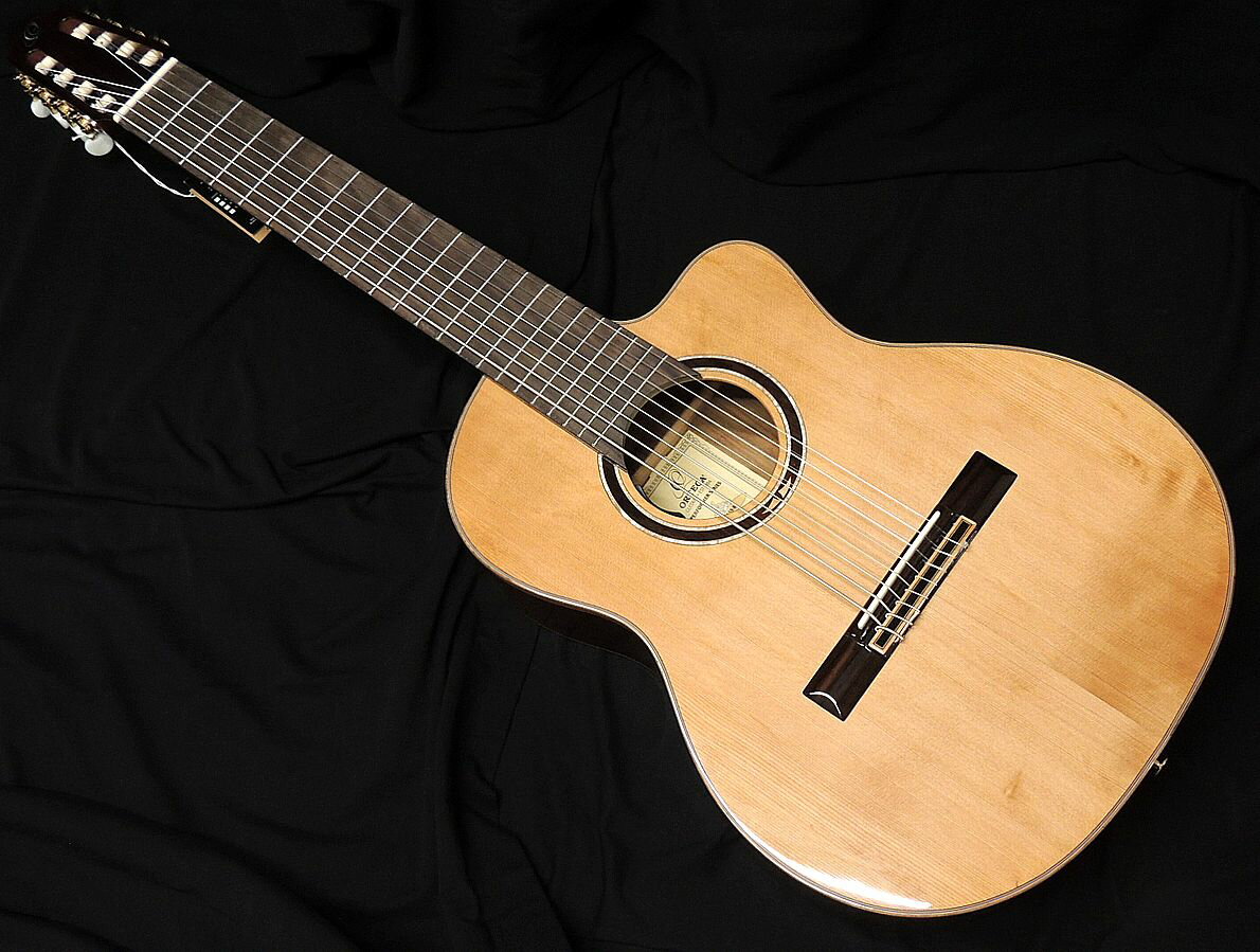 PERFORMER SERIES PERFORMER シリーズは、伝統的なスペイン製ギターの構造に現代的な要素を取り入れたシリーズです。 充電式プリアンプを搭載。 チューニング 1E/2B/3G/4D/5A/6E/7B/8F♯ ナット幅約70mm/スケール長約690mm ・ Solid North American cedar top, gloss finish ・ Walnut back & side, gloss finish ・ Mahogany neck, gloss finish ・ Tecwood fretboard & bridge ・ Ortega Magus Fly/G-8, rechargeable ・ Ortega 16 hole bridge ・ Ortega signature walnut/maple/white pearl rosette ・ 2 way truss rod built-in ・ Ortega OCTA-8NS custom made strings 定価135,000円(税抜) ギグバッグ付属