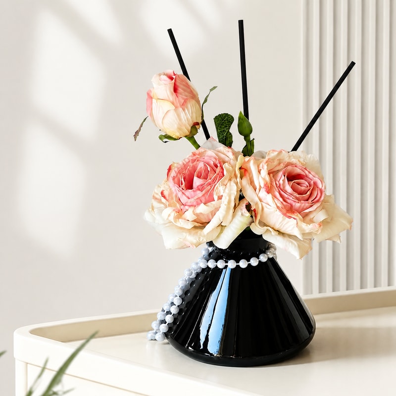 BADUSの造花付きリードディフューザー風インテリアオブジェです。商品画像では、花のアレンジ、黒い漏斗型花器、リードスティック、パールチェーンを組み合わせた置き型デザインを確認できます。SKUはローズ系8タイプとアイリス風4点セットの計9タイプです。ローズ系8タイプは選択肢名で100ml香りオイル付きの表記があります。アイリス風4点セットは4点セットとして扱い、香りオイル付属は元データだけでは断定していません。玄関、リビング、寝室、洗面まわりなどの棚上に置きやすい、花の見た目を楽しめるインテリアです。撮影用のキャンドル、本、ミラー、ボックス、タオルなどの背景小物は商品に含まれません。香りの種類、持続時間、消臭性能、花器サイズ、材質詳細、香りオイルの容器形状、認証などは元データだけでは確認できないため断定していません。ご注文前に選択中のタイプと商品画像をご確認ください。