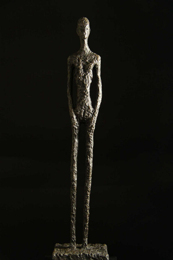 アルベルト・ジャコメッティ（Alberto Giacometti, 1901年10月10日 - 1966年1月11日）は、スイス出身の20世紀の彫刻家。 ジャコメッティはおもに彫刻家として知られるが、絵画や版画の作品も多い。第二次世界大戦以前にはシュルレアリスムの彫刻家と見なされていたが、もっともよく知られている作品群は、大戦後に作られた、針金のように極端に細く、長く引き伸ばされた人物彫刻である。これらの作品はしばしば実存主義的と評される。スイスのイタリア語圏の出身だが、おもにフランスで活動した。 ジャコメッティは、スイスのイタリア国境に近いボルゴノーヴォ（現在グラウビュンデン州マローヤ地区のスタンパの一部）に生まれ、近郊のスタンパの町で育った。父のジョヴァンニ・ジャコメッティ（1868−1933）はスイス印象派の画家であった。また、1歳違いの弟ディエゴ・ジャコメッティ（1902−1985）は兄の助手およびモデルを務め、後には家具製作者となった。 ジャコメッティは、高等学校卒業後、1919年にジュネーヴ美術学校に入学するが、入学後数日で絵画には見切りをつけ、ジュネーヴ工芸学校のモーリス・サルキソフ（1882−1946）のもとで彫刻を学んだ。1920年にヴェネツィア、1921年にはローマに滞在した後、1922年パリに転居し、アカデミー・ド・ラ・グランド・ショーミエールでロダンの弟子アントワーヌ・ブールデルに学んだ。 1920年代半ばから弟のディエゴと共同でアトリエを構え、1927年前後からパリのサロン・デ・テュイルリーで作品を発表しはじめた。この頃のジャコメッティは、写実的な彫刻にはあきたらないものを感じ、キュビスム、シュルレアリスム、原始彫刻などの影響を受けた作品を制作した。パリではピカソ、エルンスト、ミロらの画家、シュルレアリスム運動の主唱者アンドレ・ブルトンらのほか、ジャン＝ポール・サルトル、ポール・エリュアールらの文人とも交友があった。1932年作の『午前4時の宮殿』はこの頃の代表作で、シュルレアリスムの絵画を立体に移したような作品である。 彼は1935年、それまでのシュルレアリスム的作風を放棄して、再び人物モデルを写生する伝統的方法に戻り、シュルレアリストのグループからも離脱した。第二次世界大戦中の1942年にいったん故国のジュネーヴに戻り、大戦後の1946年再度パリに移住する。 ジャコメッティは大戦前にも細長い人物像を作っていたが、大戦後の1950年頃から作られはじめた人物像は、肉付けも凹凸もなく、「彫刻」としての限界と思えるほどに細長いものである。サルトルは、これらのジャコメッティの人物像を、現代における人間の実存を表現したものとして高く評価した。なお、古代イタリアのエトルリア文明にも細長く引き伸ばされた人物彫刻があり、それとの関連も指摘されている。 1962年のヴェネツィア・ビエンナーレでジャコメッティのために1室が与えられるなど、晩年には国際的に高く評価されるようになった。また晩年には絵画、版画など平面芸術への回帰もみられる。版画集『終わりなきパリ』は1958年から1965年にかけて制作した石版画150点を収録し、ジャコメッティ自身によるテキストを付したもので、晩年の代表作である。1966年、スイスのクールで没した。 1998年10月から発行されている、スイスの現行第8次紙幣の100フラン紙幣に、彼の肖像が描かれている。紙幣の裏面は「歩く男」である。 1950年半ばにフランス留学した哲学者矢内原伊作と、数年間深い交流がありモデルにした作品もある。　 ・高さ：46センチ ・幅：13センチ ・重量：2.6kg ・材質：ブロンズ及び大理石アルベルト・ジャコメッティ（Alberto Giacometti, 1901年10月10日 - 1966年1月11日）は、スイス出身の20世紀の彫刻家。 ジャコメッティはおもに彫刻家として知られるが、絵画や版画の作品も多い。第二次世界大戦以前にはシュルレアリスムの彫刻家と見なされていたが、もっともよく知られている作品群は、大戦後に作られた、針金のように極端に細く、長く引き伸ばされた人物彫刻である。これらの作品はしばしば実存主義的と評される。スイスのイタリア語圏の出身だが、おもにフランスで活動した。 ジャコメッティは、スイスのイタリア国境に近いボルゴノーヴォ（現在グラウビュンデン州マローヤ地区のスタンパの一部）に生まれ、近郊のスタンパの町で育った。父のジョヴァンニ・ジャコメッティ（1868−1933）はスイス印象派の画家であった。また、1歳違いの弟ディエゴ・ジャコメッティ（1902−1985）は兄の助手およびモデルを務め、後には家具製作者となった。 ジャコメッティは、高等学校卒業後、1919年にジュネーヴ美術学校に入学するが、入学後数日で絵画には見切りをつけ、ジュネーヴ工芸学校のモーリス・サルキソフ（1882−1946）のもとで彫刻を学んだ。1920年にヴェネツィア、1921年にはローマに滞在した後、1922年パリに転居し、アカデミー・ド・ラ・グランド・ショーミエールでロダンの弟子アントワーヌ・ブールデルに学んだ。 1920年代半ばから弟のディエゴと共同でアトリエを構え、1927年前後からパリのサロン・デ・テュイルリーで作品を発表しはじめた。この頃のジャコメッティは、写実的な彫刻にはあきたらないものを感じ、キュビスム、シュルレアリスム、原始彫刻などの影響を受けた作品を制作した。パリではピカソ、エルンスト、ミロらの画家、シュルレアリスム運動の主唱者アンドレ・ブルトンらのほか、ジャン＝ポール・サルトル、ポール・エリュアールらの文人とも交友があった。1932年作の『午前4時の宮殿』はこの頃の代表作で、シュルレアリスムの絵画を立体に移したような作品である。 彼は1935年、それまでのシュルレアリスム的作風を放棄して、再び人物モデルを写生する伝統的方法に戻り、シュルレアリストのグループからも離脱した。第二次世界大戦中の1942年にいったん故国のジュネーヴに戻り、大戦後の1946年再度パリに移住する。 ジャコメッティは大戦前にも細長い人物像を作っていたが、大戦後の1950年頃から作られはじめた人物像は、肉付けも凹凸もなく、「彫刻」としての限界と思えるほどに細長いものである。サルトルは、これらのジャコメッティの人物像を、現代における人間の実存を表現したものとして高く評価した。なお、古代イタリアのエトルリア文明にも細長く引き伸ばされた人物彫刻があり、それとの関連も指摘されている。 1962年のヴェネツィア・ビエンナーレでジャコメッティのために1室が与えられるなど、晩年には国際的に高く評価されるようになった。また晩年には絵画、版画など平面芸術への回帰もみられる。版画集『終わりなきパリ』は1958年から1965年にかけて制作した石版画150点を収録し、ジャコメッティ自身によるテキストを付したもので、晩年の代表作である。1966年、スイスのクールで没した。 1998年10月から発行されている、スイスの現行第8次紙幣の100フラン紙幣に、彼の肖像が描かれている。紙幣の裏面は「歩く男」である。 1950年半ばにフランス留学した哲学者矢内原伊作と、数年間深い交流がありモデルにした作品もある。　 ・高さ：46センチ ・幅：13センチ ・重量：2.6kg ・材質：ブロンズ及び大理石