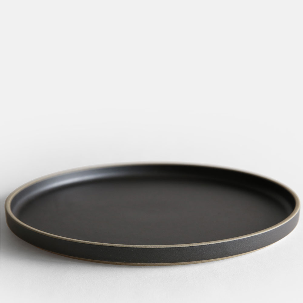 Brand : HASAMI PORCELAIN（ハサミポーセリン） Item : PLATE(Black) / HPB006 / プレート 「HASAMI PORCELAIN」（ハサミポーセリン）は伝統的な遺産を現代的なコンセプトでデザインした波佐見焼のテーブルウェアシリーズです。ディレクションはアメリカ西海岸に拠点を置くデザイナー、篠本拓宏さんによるもの。全てのアイテムが一定のモジュールに従ってサイズ設計されているので、スタッキングや入れ子にして収納が可能になっていたりと機能的にも優れています。 【サイズ】：φ300×H21mm 【材質】：半磁器 【生産地】：長崎県波佐見町 【お取り扱いについて】：電子レンジ：○　/　食洗機：○　/　オーブン：× /　直火：× 日本有数の窯業の盛んな地、長崎県波佐見町。この地で約400年前の江戸時代につくられはじめた磁器は、当時から日本各地はもとより、長崎港を経てヨーロッパへも出荷されていました。早くから量産体制が整えられたため、日用の食器としての確かな質と価格を実現したことが知られています。豊かな伝統は、現代まで脈々と受け継がれ、HASAMI PORCELAINは、篠本拓宏（tortoise）のディレクションにより、こうした遺産を現代のコンセプトで革新するテーブルウェアとして生まれました。 HASAMI PORCELAIN（ハサミポーセリン）のアイテム一覧HASAMI PORCELAIN（ハサミポーセリン） 伝統的な遺産を現代的なコンセプトでデザインした波佐見焼のテーブルウェアシリーズ item:PLATE(Black) / HPB006 price:9,000yen+tax brand:HASAMI PORCELAIN（ハサミポーセリン） derection:篠本拓宏（tortoise） 「HASAMI PORCELAIN」（ハサミポーセリン）は伝統的な遺産を現代的なコンセプトでデザインした波佐見焼のテーブルウェアシリーズです。ディレクションはアメリカ西海岸に拠点を置くデザイナー、篠本拓宏さんによるもの。全てのアイテムが一定のモジュールに従ってサイズ設計されているので、スタッキングや入れ子にして収納が可能になっていたりと機能的にも優れています。 SPEC サイズ φ300×H21mm 材質 半磁器 生産地 長崎県波佐見町 お取り扱いについて 電子レンジ：○　/　食洗機：○　/　オーブン：×　/　直火：× 波佐見から世界へ 日本有数の窯業の盛んな地、長崎県波佐見町。 この地で約400年前の江戸時代につくられはじめた磁器は、当時から日本各地はもとより、長崎港を経てヨーロッパへも出荷されていました。 早くから量産体制が整えられたため、日用の食器としての確かな質と価格を実現したことが知られています。豊かな伝統は、現代まで脈々と受け継がれ、HASAMI PORCELAIN（ハサミポーセリン）は、篠本拓宏（tortoise）のディレクションにより、こうした遺産を現代のコンセプトで革新するテーブルウェアとして生まれました。 アメリカで先行発売され人気となり、2011年に日本でも発売されて以来注目を集め、今ではスタンダードなテーブルウェアとして定着しています。 考え抜かれたモジュール設計 HASAMI HASAMI PORCELAIN（ハサミポーセリン）の器のサイズは、8.5cm、14.5cm、18.5cm、22cm、25.5cm、30cmのモジュールに従って設計されています。マグカップ、ボウル、トレイなど個々のアイテムが共通の直径でデザインされているため、自由なスタッキングが可能で、収納時や運搬時も無駄がありません。ニーズに合わせてスタッキングできる仕組みや、異なるサイズの器が入れ子で収納できる機能性は、日本料理のための伝統的な漆器である重箱からインスピレーションを得ています。重箱と同じように、室内でもアウトドアでも、単体でもセットでも、幅広いシーンで自由に使うことができます。 普遍性が宿る無駄のない佇まい HASAMI PORCELAIN（ハサミポーセリン）のフォルムには、一切の装飾性がありません。日本の伝統的な形態の根本でもある、潔くすっきりとした直線。機能と製造工程の必然性から導かれた、意味のある曲線。シンプルな線のみで構成されたデザインは、いくつもの器が重なり合い、フォルムがリピートすることで、いっそう美しい調和をつくり出します。「HASAMI PORCELAIN」（ハサミポーセリン）の無駄のない佇まいには、生活のための道具にふさわしい普遍性が宿っているのを感じます。 料理が映えるフォルムとカラー シンプルなフォルムとベーシックなカラー（ナチュラル、ブラック、グロスグレー）の器は料理を引き立ててくれます。まるで絵を描くように料理を盛り付けてお楽しみ頂けます。またサイズ展開が豊富ですので、あらゆる料理に対応したテーブルコーディネートが可能です。また電子レンジや食洗機も対応しておりますので、日常使いの器として気兼ねなくお使い頂けます。 触れた時の心地よさ HASAMI PORCELAIN（ハサミポーセリン）の魅力は、器が手や口に触れた時の感覚にある。陶器に比べて引き締まったシャープさがあり、通常の磁器よりも優しく有機的な感触が心地よい。独特の素材感によってもたらされるマットな風合いと色彩は、どんな食材と合わせても違和感がなく、フードやドリンクを引き立ててくれる。 HASAMI PORCELAIN（ハサミポーセリン）の素地は、天然の天草陶石からつくられる磁器の原料に、独自の比率で陶土を混ぜたもの。以前に波佐見で焼かれた陶磁器のサンプルを再現し、ありのままの素材感を生かす釉薬が配合された。 BRAND VARIATION こんな商品もおすすめ