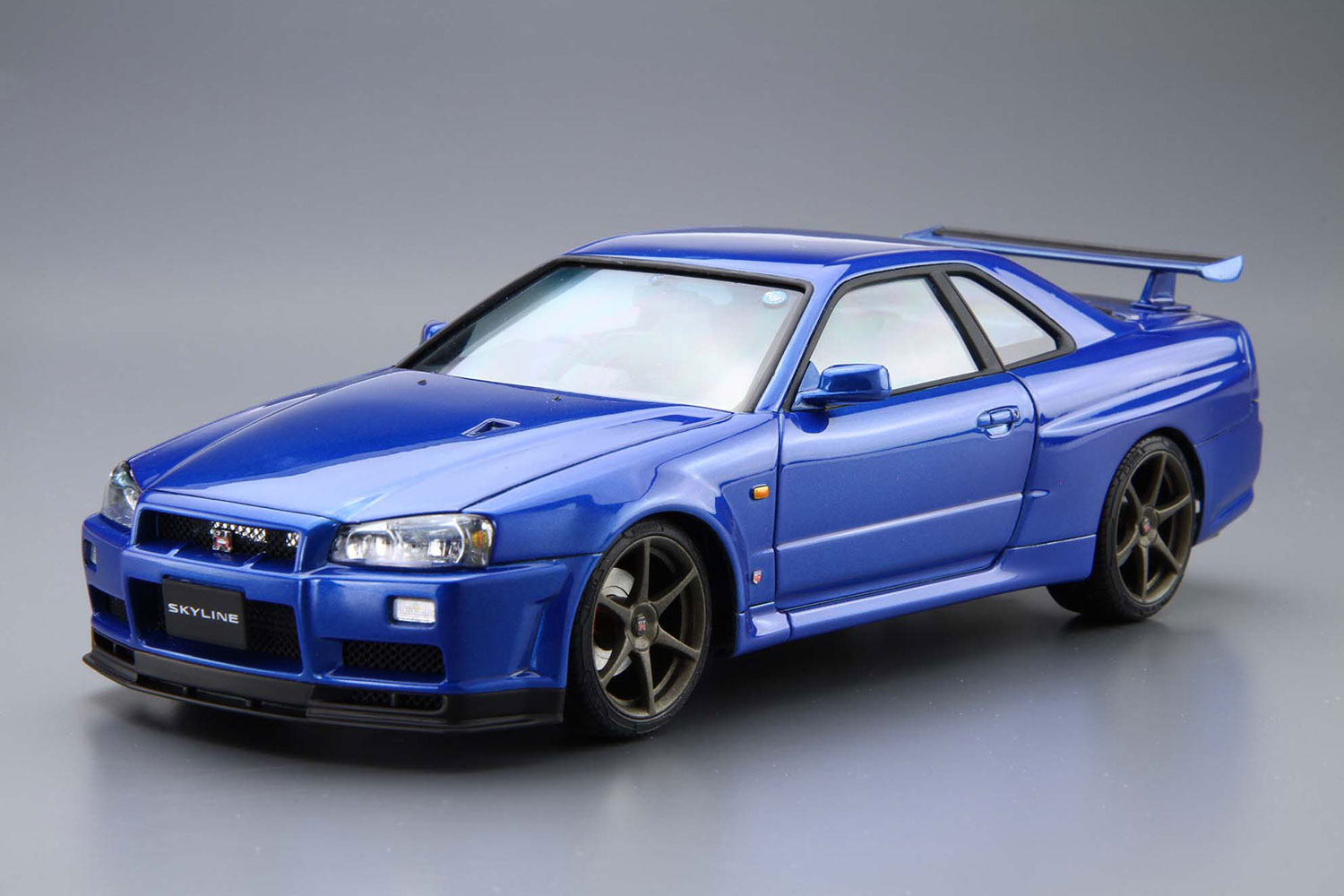究極へ。R34 GT-R

1999年1月、それまで「最強」の称号を欲しいままにしてきた R33型スカイラインGT-Rを基に 、R34型スカイラインGT-R (BNR34) は生まれました。
パワーユニットはR32 型から引き継がれてきた名機「RB26DETT」を更にリファインし、最高出力は当時の国内自主規制値280psに抑えられているものの、トルクは40.0kg-m、リッターあたり15.6kg-mと当時の国産エンジン最強スペックを誇りました。
また、トランスミッションはゲトラグ社と共同開発した6速マニュアルを採用しています。
ボディサイズもR33 型と比べダウンサイジングが図られ、運動性能を大幅に高めました。
しかし2002年8月、排ガス規制のため惜しまれつつ生産を終了し、その歴史に幕を閉じています。

ボンネットの「NACAダクト」を再現
スプリングサスペンション色分け成型
テールランプはクリアレッド着色済み
アルミナンバープレート付属
窓枠マスキングシール付属
18インチタイヤ使用

※画像は試作品です。実際の商品とは異なる場合がございます。

・ホビー系商品についての諸注意
メーカー都合により発売の大幅な延期が発生する可能性がございます。
予約商品についてはメーカーから順次入荷次第の発送となります。メーカー公表の発売日とは異なる場合がございますのでご了承ください。【対象年齢】：