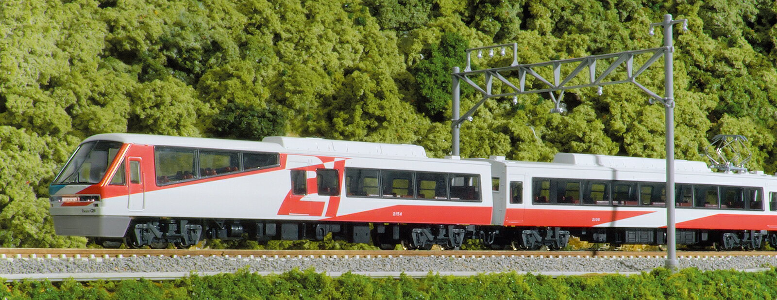 伊豆急行の2100系は、「21世紀へ進む鉄道車両へのひとつの提案」として設計・製造された車両で昭和60年(1985)にデビューし「リゾート21」の愛称で親しまれています。
大形の前面窓と階段状の展望席のある先頭車や海の車窓を楽しめるように窓側を向いた座席が採用されているほか、海側の窓は大形の連続展望窓が採用されています。
塗色も左右で異なるため、見る側によって印象が大きく異なる個性的な車両です。

令和7年(2025)7月にデビュー40周年を迎えた伊豆急行の人気車両、2100系「リゾート21」が久々の登場です。
登場当初のトリコロールのカラーリングにグレーのスカート、「Izukyu」マーク掲出前の塗色を再現いたします。
好評発売中の〈10-1848〜1850 211系0/2000番台〉や〈10-1954〜1956 113系 2000番台 湘南色(JR仕様)〉など、東京〜伊豆急下田間で出会う車両製品とあわせてお楽しみいただけます。

活躍地域
・中部

会社
・私鉄

製品特徴
・2次車に分類されるR-2編成を製品化
・昭和61年(1986)の登場からロイヤルボックスが増結される平成3年(1991)頃までの形態を再現
・大きな窓ガラスの先頭車前面部、車体側面に「21」をあしらった大胆で斬新なカラーリングを再現
・先頭車側面の「Izukyu」ロゴなし、スカートはグレーで再現
・動力ユニットはGM-5モーターを搭載。安定した走行が可能
・ヘッド/フォグ/テールライト、前面行先表示器点灯(白色LED採用)
・中間車連結部はジャンパ管付KATOカプラー密連形を採用
・行先表示シール付属

製品内容・編成図
←伊豆急下田・伊豆高原
クハ2154
モハ2107
モハ2108(M)
サハ2172
モハ2106
モハ2105
クハ2153
熱海→

製品仕様
・スケール：1/150 9mm(Nゲージ)
・商品形態：塗装済完成品
・車体の材質：プラスティック
・モーター：動力ユニット搭載
・ライト：ヘッドライト・テールライト点灯
・付属品：行先表示シール×1

・ホビー系商品についての諸注意
メーカー都合により発売の大幅な延期が発生する可能性がございます。
予約商品についてはメーカーから順次入荷次第の発送となります。メーカー公表の発売日とは異なる場合がございますのでご了承ください。【対象年齢】：8歳以上