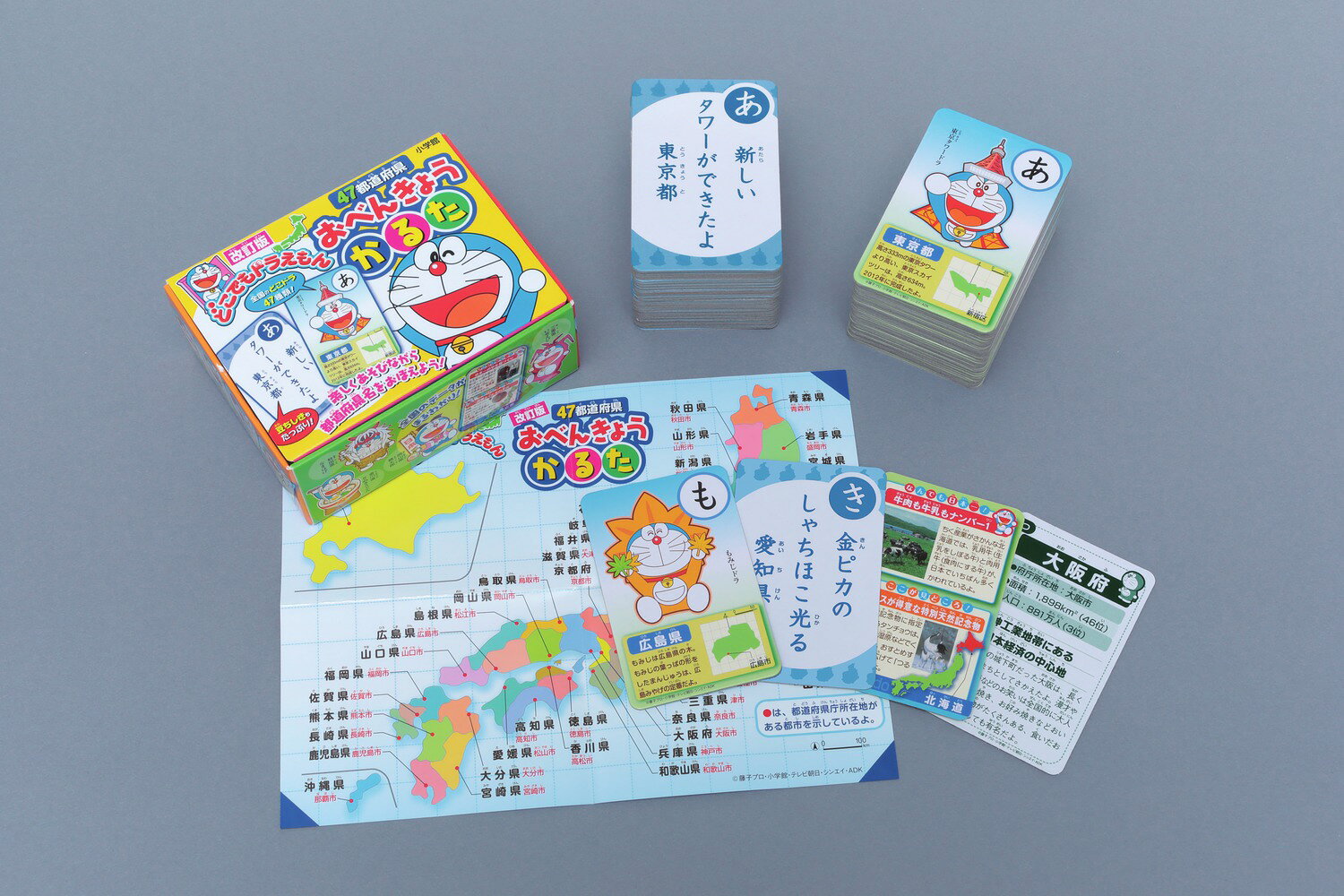 どこドラで、都道府県について学べるかるた 

 遊びながら各都道府県の特色などを学べるかるたです。

かるたには各県の特産物や歴史上の人物、お祭りなどの特性をモチーフにしたご当地キャラクターのドラえもん「どこでもドラえもん（どこドラ）」を配しました。

青森県はねぶた、熊本県はすいか、岡山県は桃太郎など、各地の特色、名所にちなんだ「どこドラ」は、お子さんの地域に関する興味をひき出します。

絵札カードには、各都道府県の位置、形、名所、「なんでも日本一！」「ここが見どころ！」などの情報を掲載。

字札カードでは県庁所在地、面積、人口、産業や特産物を紹介していますので
楽しく遊びながら、日本の地理と47都道府県について詳しくなれる、教材としてもお使いいただけます。

かるたカードは予備を含め96枚。ケース入りです。