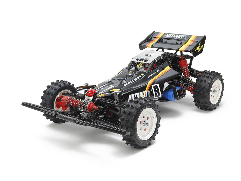 【 ブラックボディが精悍、高性能4WDバギーの進化形 】
1985年にタミヤ初の本格4WDレーシングバギーとしてデビューし、高い人気を集めたホットショット。
その基本構成を受け継いで各部を改良。
組み立てやすさや整備性、操縦性を高めて1987年に登場したホットショットIIの復刻モデルです。
低く構えたスマートなボディと、スタイリングの大きな特徴でもあるリヤウイングはポリカーボネート製。
どちらも精悍なブラックで塗装し、カット加工も施しました。
また、戦闘的なフォルムをいっそう強調するイエロー/オレンジのラインや車名ロゴなどはステッカーで用意。
あの頃あこがれたマシンが手軽に仕上がります。

【 ハイスピード4WDバギーの方向性を示したタフなシャーシ構成 】
シャーシはオリジナルのホットショットIIのコンセプトを引き継ぐシャフトドライブ4WD。
強度の高いモノコックフレームの前後に、砂や小石の侵入を防ぐ密閉式ギヤボックスを搭載。
スムーズな作動と素直な操縦性を生み出すデフギヤを内蔵しました。
また、バッテリーカバーを兼ねるアンダーガードも付いています。
サスペンションはフロント1本・リヤ2本のCVAオイルダンパーを備えたダブルウィッシュボーン4輪独立。
前輪にはスタビライザーをセットして、しなやかな足まわりが四駆パワーを有効に生かします。
さらに、ホワイトのディッシュホイールにはオーバルブロックとピンスパイクを組み合わせた中空ゴム製ロープロファイルタイヤを装着。
高いグリップ力と4WDで悪路も難なく走破します。

【 基本スペック 】
●全長390mm、全幅235mm、全高160mm 
●ホイールベース265mm 
●タイヤ幅/径=前31/88mm、後38/88mm 
●トレッド=前205mm、後200mm 
●フレーム=ABS樹脂製モノコック 
●駆動方式=シャフトドライブ4WD 
●デフギヤ=前後3ベベル 
●ステアリング=2分割タイロッド式 
●サスペンション=4輪ダブルウィッシュボーン 
●ダンパー=前後ともCVAオイルダンパー 
●ギヤ比=10.04:1、8.70:1、8.16:1、7.68:1の4種類から選択可能 
●モーター=RS540タイプ 
●スピードコントローラー=ESC仕様(別売)

【 別にお求めいただくもの 】 
●ファインスペック 2.4G 電動RCドライブセット　
●送信機用単3形電池4本

・ホビー系商品についての諸注意
メーカー都合により発売の大幅な延期が発生する可能性がございます。
予約商品についてはメーカーから順次入荷次第の発送となります。メーカー公表の発売日とは異なる場合がございますのでご了承ください。【対象年齢】：【商品サイズ (cm)】(幅×高さ×奥行）：39×16×23.5