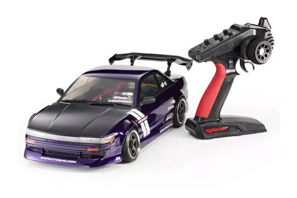 ドリフト専用シャシー＆メカ搭載
これがドリフトR/Cの真のスタンダード！
パッケージから取り出して車体に充電したバッテリーを搭載し、送信機に乾電池を入れればすぐに走行可能な手軽さが魅力のFAZERシリーズのレディセットに、待望のRWDドリフトモデル『FAZER D2』が登場します！　
リア2輪駆動（RWD）は、現在の1/10スケールドリフトR/Cカーで最もポピュラーな駆動方式で、実車さながらに大きくカウンターステアを切ってドリフトする姿が高い人気を集めています。
こちらのFAZER D2は、従来のFAZERシリーズとは全く異なるドリフト専用RWDシャシーを採用し、重量配分やサスペンションの設計をドリフトに最適化すると同時に、車体のスライドに応じて自動的にカウンターステア操作などを行ってくれるジャイロユニット内蔵型の受信機も装備しています。
注目はこのジャイロがステアリングだけでなくスロットルの制御も行うことで、これまでドリフトR/Cカーを操縦した経験のない人も完璧にサポートします。
もちろんシャシーも快適なドリフト走行を実現するため、ロングスパンサスアームやハイマウントモーターの採用など、近代ドリフトR/Cカーのトレンドを取り入れつつ扱いやすさやセッティングにも配慮。
完成済みレディセットであっても、パーツの変更などによって本格R/Cカーならではのセッティング&チューンアップを楽しむことができます。
ドリフト走行の雰囲気を高めるためには欠かせないボディは京商の誇るウルトラスケールボディで展開し、多彩なボディの搭載を可能にするホイールベース可変機能も搭載しました。
従来は、ある程度の経験があるユーザー向けというイメージの強かった1/10スケールのドリフトカーですが、完成済みレディセットFAZER D2の登場によって一気に身近なものとなります。


『ULTRA SCALE BODY PLUS』とは？
ボディ、ライトバケット、バンパー、ミラーを忠実に再現しており、クルマとしての造形の細部まで徹底的に作り込んだ　“走るディスプレイモデル”とも呼ぶべき『ULTRA SCALE BODY』が、ポリカーボネートボディに穴を開けない『ULTRA SCALE BODY PLUS』としてスケールをさらに追求。

●送信機用の乾電池と走行用バッテリー＆充電器を準備することで即ドリフト走行が可能なレディセット。
●ボディはドリフトシーンを彷彿とさせるオリジナルエアロパーツを装着したデザインにカスタマイズ。
●”ウルトラスケールボディプラス”仕様のボディには、LED搭載可能のライトバケット他、精巧なディティールを実現したプラパーツを使用。
●新設計の2ピースホイールは、5/7/9mmとオフセットを変更することが可能。ホイールデザインは、”fifteen52”の”Turbomac”を採用。
●シャシーは、ホイルベース可変式でFAZERシリーズのほとんどのボディを搭載可能。
●ステルスボディマウント採用により、ボディポストが外観上見えないのでスケール感が向上。従来のFAZERシリーズにも対応するピン固定式のボディマウントも付属。
●タイヤはPP（ポリプロピレン）製で様々な路面に対応。※サーキットで指定がある場合は変更の必要あり。
●ドリフトに適したKS4072-06Wサーボを採用。モーターは初心者にも扱いやすい『G22ブラシモーター』を採用。
●ギヤカバーを標準装備しパーキングロット等砂利の多いところでの走行にも対応。また回転部を隠すことでケガの防止にも一役。
●バッテリーはショートリポからストレートパックまで市場のほとんどのものが搭載可能。※LCGタイプはスペーサー（5〜6mm厚のスポンジシートで可）が別途必要
●ジャイロと受信機が一体の『KRG-331D』。ステアリングゲインに加えスロットルゲインも装備し初心者の走行をサポート。
●モーターマウントにはバックラッシュが最適な位置になる取付穴がありメンテ時に脱着した場合も調整不要。ギヤ比変更時は長穴の使用で微調整可能。
●オイルダンパーを標準装備。ピストン・スプリング・オイルはドリフト専用のセッティングを施しドリフト走行をサポート。またセッティング用のピストンも同梱。
●サスホルダー等の向きを変更することで、キャスター角・アッカーマン・ロールセンターを変更可能。
●標準では一体型ロッドの採用でフロントのトーイン、リヤキャンバー角は最適な位置に設定。フロントキャンバーのみカラー変更で調整可能。
●購入後もカーボンシャシーやアルミダンパーステー等様々なオプションパーツでグレードアップが楽しめる。

テクニカルデータ
■全長（ボディ含） 483mm
■全幅（ボディ幅 ※ミラー除く） 204mm
■全幅（シャシー） 208mm
■全高（ボディ含） 130mm
■シャシー高 12mm
■ホイールベース 260mm ※(240-273mm可変）
■トレッド（F）172mm
■トレッド（R）180mm
■ギヤレシオ 9.1：1
■タイヤ（F/R）φ63×24mm
■全備重量 約1,450g
■モーター G22ブラシモーター
■使用プロポ シンクロKT-231P+

キット内容
＜キット内容＞
●R/Cユニット組込み済み工場完成シャシー
●カラーリング・デカール・組み立て済みボディ
●シンクロKT-231P+送信機
●1.5mm/2.0mm 六角レンチ
●十字レンチ（小）
●セッティング変更パーツ

走行までに必要なもの
●送信機用単3乾電池4本
●走行用バッテリー
　 推奨：KYOSHO SPEED HOUSE 7.2V 22HV Ni-MHバッテリー 71322B
　　　　 KYOSHO SPEED HOUSE 7.2V 36HV Ni-MHバッテリー 71324B
●走行バッテリー用充電器
　 推奨：KYOSHO SPEED HOUSE C-02B ACピークチャージャー72002B ※Ni-MH専用充電器
　　　　 7.2V NiMH用 USBチャージャー 72204 ※Ni-MH専用充電器
●各種工具

・ホビー系商品についての諸注意
メーカー都合により発売の大幅な延期が発生する可能性がございます。
予約商品についてはメーカーから順次入荷次第の発送となります。メーカー公表の発売日とは異なる場合がございますのでご了承ください。【対象年齢】：