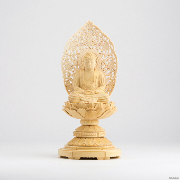 釈迦如来像（座像）は曹洞宗・臨済宗・天台宗のご本尊などとしておまつりします。 モダンミニ仏壇・上置仏壇・手元供養壇などに、ちょうど良い小さめのサイズです。 小さいお仏壇でも、ご本尊をお仏像にされることで、より荘厳な雰囲気となることでしょう。 材質は柘植（つげ）を使っています。硬くて木肌の細かい高級材です。細かいところも手仕事で、丁寧に彫り込んであります。 光背（こうはい）は、標準的な「唐草光背」です。手作業で細かいところまで彫ってあり、ご本尊を美しく引き立てます。 台座は、シンプルな「丸台座」です。六角台座などに比べると低く小さいので、ご本尊をコンパクトにおまつりすることができます。 お届け時は、台座・仏身・光背の3点に分かれた状態でお届けします。ごく簡単な組み立てをお願いいたします。 ※手作りですので、一体ごとに表情や彫りの細かい部分、サイズが若干異なります。また、天然木を使用しておりますので、木目、色などにも、違いがございます。予めご了承下さいますようお願い致します。 ※天台宗の方へ 天台宗では、お仏壇へおまつりするご本尊は特に規定がなく、こちらの釈迦如来像（座像）の他に、阿弥陀如来像（座像）等の場合もございます。ご不明の場合はお寺様へご相談下さい。 ■サイズ：高さ20.2cm 幅9.3cm 奥行8.8cm ■材質：柘植（つげ）製 ［仏像］［釈迦如来］［柘植製］［丸座］［2寸］［金泥書無し］［曹洞宗］［臨済宗］［天台宗］［おしゃか様］［シャカ］［しゃか］［総柘植］［つげ］［ツゲ］［2寸］［2.0寸］［2．0寸］［二寸］［丸台座］［丸台］［蓮華座］［唐草光背］［仏壇用］［ご本尊］［御本尊］［白木］［白い木］［明るい色］［木像］［butuzou］［小さい］［小さな］［ミニ］仏像 釈迦如来 ツゲ製 丸座 2.0寸 木地 釈迦如来像（座像）は曹洞宗・臨済宗・天台宗のご本尊などとしておまつりします。 モダンミニ仏壇・上置仏壇・手元供養壇などに、ちょうど良い小さめのサイズです。 小さいお仏壇でも、ご本尊をお仏像にされることで、より荘厳な雰囲気となることでしょう。 材質は柘植（つげ）を使っています。硬くて木肌の細かい高級材です。 細かいところも手仕事で、丁寧に彫り込んであります。 ※手作りですので、一体ごとに表情や彫りの細かい部分、サイズが若干異なります。また、天然木を使用しておりますので、木目、色などにも、違いがございます。予めご了承下さいますようお願い致します。 こちらの商品は、仏身に色をつけていない「木地」です。 金色の顔料で、衣や装飾品などを描いた「金泥書」の商品もございます。 →お仏像の一覧から 光背（こうはい）は、標準的な「唐草光背」です。手作業で細かいところまで彫ってあり、ご本尊を美しく引き立てます。 台座は、シンプルな「丸台座」です。六角台座などに比べると低く小さいので、ご本尊をコンパクトにおまつりすることができます。 お届け時は、台座・仏身・光背の3点に分かれた状態でお届けします。ごく簡単な組み立てをお願いいたします。 お仏像は、お仏壇の最上段中央におまつりします。ご購入の際はお仏壇の最上段から天井までのサイズとお仏像の総高さを、また、お仏壇最上段の奥行とお仏像の奥行をご確認くださいませ。 商品名の「○○寸」というサイズ表記は、眉間の白毫（びゃくごう）から足元までの、おおよその高さを表しています。 ※手作りですので、一体ごとに表情や彫りの細かい部分、サイズが若干異なります。また、天然木を使用しておりますので、木目、色などにも、違いがございます。予めご了承下さいますようお願い致します。 身長170cmの男性の手です。 サイズ展開としては、「2.0寸」「1.8寸」「1.5寸」をご用意いたしております。 こちらは「2.0寸」の商品ページです。 その他のサイズや材質違いのバリエーションは、 →お仏像の一覧へ ■天台宗の方へ 天台宗では、お仏壇へおまつりするご本尊は特に規定がなく、こちらの釈迦如来像（座像）の他に、阿弥陀如来像（座像）等の場合もございます。ご不明の場合はお寺様へご相談下さい。