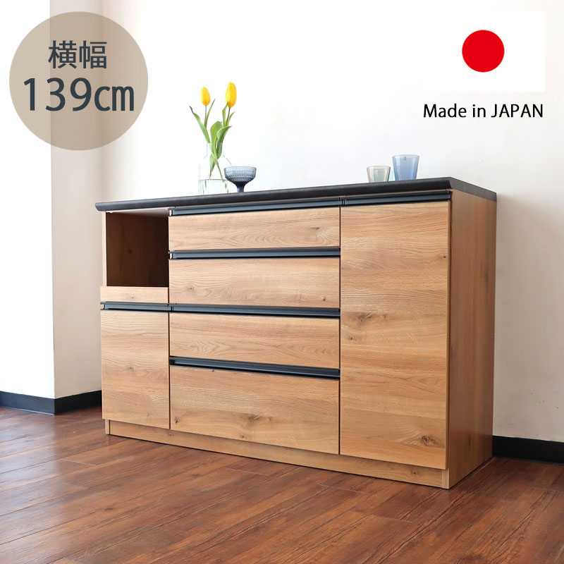 商品説明サイズ本体：幅139cm×奥行48cm×高さ90cm オープンスペース内寸：幅32cm×奥行43.3cm×29.5cm 材質化粧板/MDF備考開梱設置にてお届けです。店長コメントオーク材の美しい木目と機能性を融合させた、幅140cmの国産キッチンカウンターです。 シンプルでモダンなデザインだからこそ、随所にちりばめられた細部のこだわりが際立ち、上質な空間を演出します。 本体には、オーク材・節あり柄の高品質シートを使用。 まるで天然木のようなリアルな質感が特徴で、家具業界に長く携わる店長自身も、近くで見ないと見分けがつかないほどの完成度と感じています。 天然木に比べて扱いやすく、反りや割れの心配が少ない点も魅力です。 引き出しにはブルモーション機能（ソフトクローズ）を搭載。 軽く押すだけでゆっくりと静かに閉まり、開閉時の衝撃を抑えます。 開き扉部分も同様にソフトクローズ仕様となっており、快適な使い心地を実現しています。 内部の棚は可動棚仕様となっており、収納物に合わせて高さ調整が可能です。 また、オープンスペースと炊飯器収納部分には、調湿・消臭効果に優れたモイス材を採用。 蒸気や湿気を抑え、収納内部を快適な状態に保ちます。 国内工場にて丁寧に製作された国産家具ならではの確かな品質で、長く安心してお使いいただけるキッチンカウンターです。