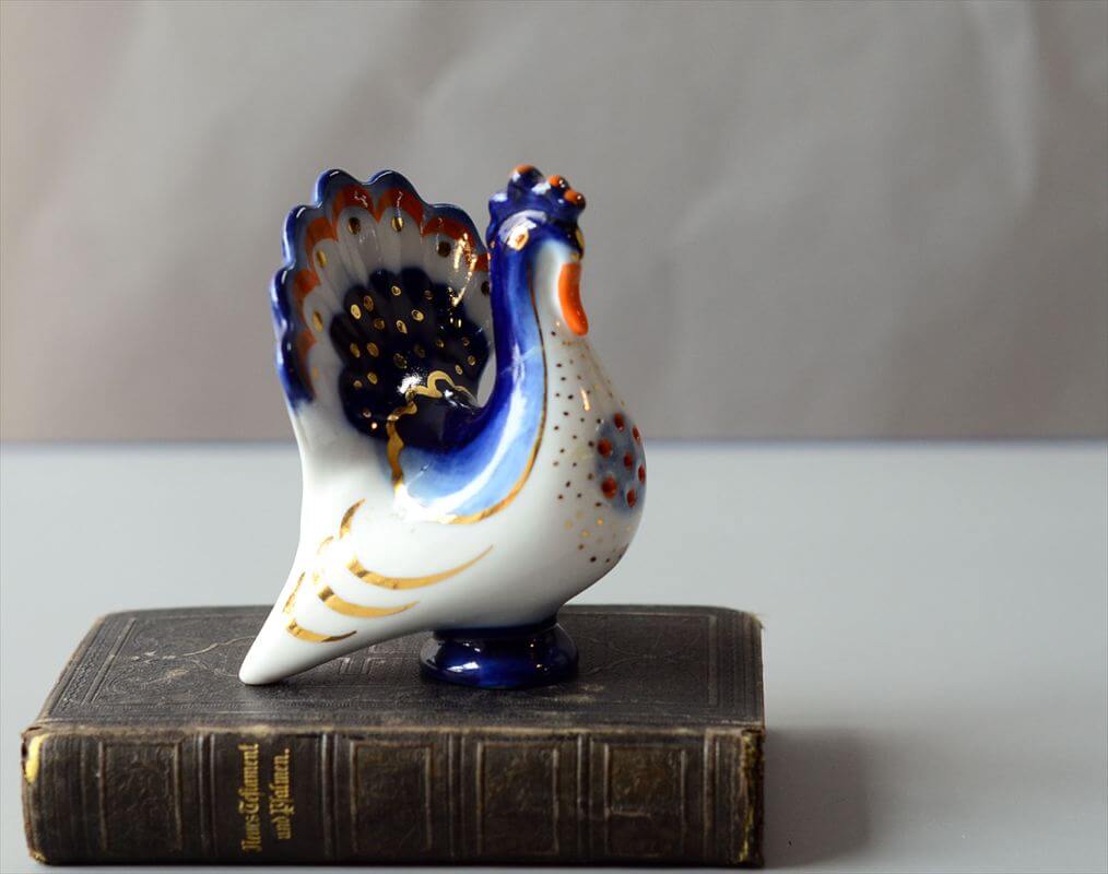 雰囲気ある古い東欧ポーセラートの空気感を演出！USSR・旧ソビエト製名門セラミックブランド・Lomonosovの雄鶏です。元々はソルト＆ペッパーだったものが底蓋の欠損によりオブジェとして愛用されていたものになります。上質な白磁に巧みな絵付けで東欧を席巻した名門。こちらのニワトリもユニークなカラーリングでとても雰囲気があります。置いたその場をただかわいいだけではない洗練された空気感と一緒に彩ってくれますサイズ(cm)状態全長 8.5高さ 9.3幅 6.8若干の誤差はご了承くださいUSED首の破損がリペアされているための訳あり品になります。グラつきなどはありません。素材原産国磁器ソヴィエト【送料無料】訳あり 東欧 USSR製 Lomonosov 白磁の雄鶏 ロモノーソフ フィギュア 旧ソ連 ソビエト時代 ニワトリ ヴィンテージ アンティーク_260220雰囲気ある古い東欧ポーセラートの空気感を演出！USSR・旧ソビエト製名門セラミックブランド・Lomonosovの雄鶏です。元々はソルト＆ペッパーだったものが底蓋の欠損によりオブジェとして愛用されていたものになります。上質な白磁に巧みな絵付けで東欧を席巻した名門。こちらのニワトリもユニークなカラーリングでとても雰囲気があります。置いたその場をただかわいいだけではない洗練された空気感と一緒に彩ってくれますサイズ・実寸値(cm)全長 8.5高さ 9.3幅 6.8若干の誤差はご了承ください素材磁器原産国ソヴィエト状態・注意点USED首の破損がリペアされているための訳あり品になります。グラつきなどはありません。備考お店のトップに戻る