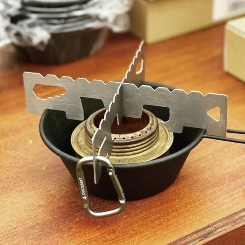 アルコールストーブの風防対策として用いられるシェラカップ。そのシェラカップ掛けられる燃焼効率を考慮した専用ゴトク。軽量でコンパクト設計、カラビナで纏められて、持ち運びも快適。ソロキャンプや登山などに最適！ブレイクタイムが華やぎます。口径φ85mm〜120mmのシェラカップやクッカー類に対応しています。サイズ／ゴトク：縦35×横150mm・重量約34gカラビナ：縦48×横28mm・重量約4g素材／ゴトク：純チタンカラビナ：アルミ ※こちらの商品は店舗と在庫を共有しています。 ご注文時に在庫があっても、商品発送準備の段階で在庫が無い場合があります。