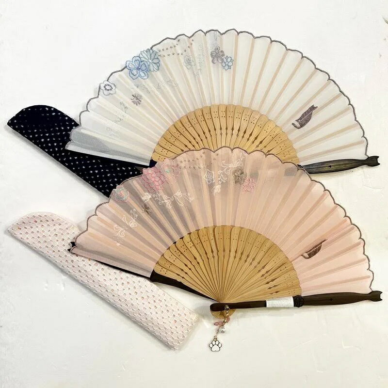 猫の刺繍と肉球チャームがかわいい、 和服にも洋服にも合うおしゃれなデザインの扇子です。 サイズ／（使用時）横幅36cm　×　長さ20cm 材質：扇面　ポリエステル　／　扇骨　竹 産地：扇面　日本　／　扇骨　中国 収納袋： 横幅5cm　×　縦幅23cm ※一つ一つの形状や大きさ・色合いに多少のズレが生じます。 【セット内容】 扇子・ 扇子袋 紙箱入り　
