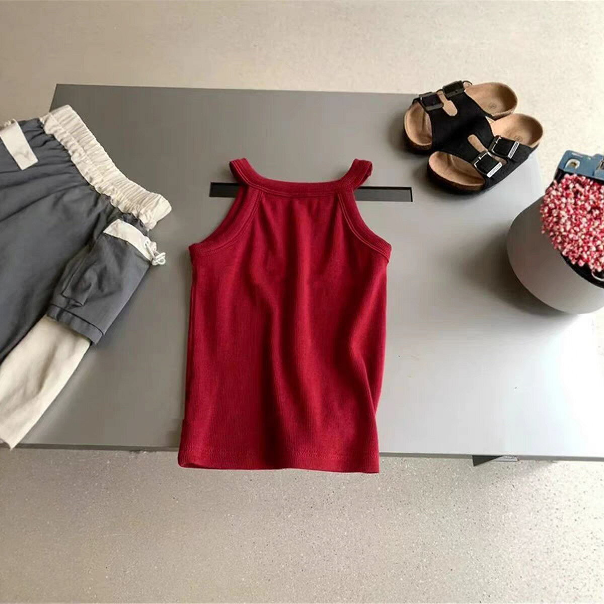 対象年齢：ベビーキッズジュニア（80cm～140cm）性別：男女兼用素材：ポリエステルカラー：レッド / ネイビー / グレー / パープル / イエロー / ホワイト / オレンジ（全 7 色）特徴：無地、太め肩ひも、通気性吸汗性、伸縮性、洗濯耐久性、インナーアウター兼用こちらは、夏のコーデに欠かせない、肌触りの良い無地キッズキャミソールです。7 色の豊富なカラーバリエーションで、どんなボトムスにも合わせやすく、重ね着にも大活躍します。デザインシンプルなホルターネックデザインで、肩ひもが太めでズレにくく、お子様の動きを邪魔しません。無地のシンプルデザインなので、カジュアルコーデからフォーマルな場面まで、幅広く対応できます。インナーとしてもアウターとしても使える、夏の万能アイテムです。