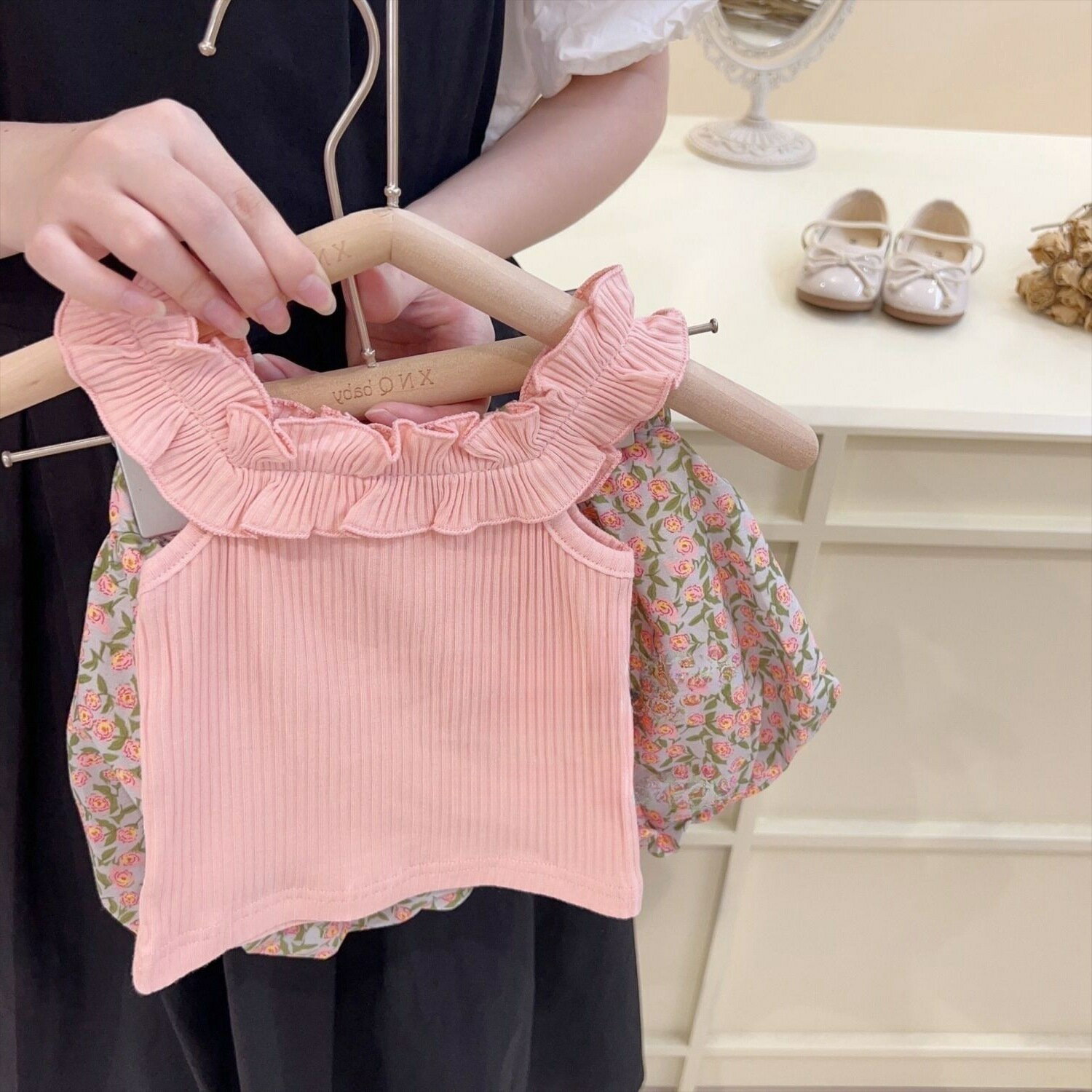 【商品説明】こちらは、可愛らしいフリルと花柄が魅力の、女の子向けキッズセットアップです。ノースリーブトップスとバルーンパンツの上下セットで、2 種類のカラーからお選びいただけます。デザイントップスは、肩元のフリルがアクセントになったリブ素材のノースリーブ。肌にフィットしつつ、締め付け感が少なく快適です。パンツは、ふんわりとした花柄のバルーンシルエットで、動きやすく、体型カバーも叶います。裾の丸みが可愛らしく、お子様のおしゃれ心をくすぐります。2 色展開：ラベンダー：トップスがラベンダー、パンツがカラフルな花柄ピンク：トップスがピンク、パンツがピンクの小花柄どちらも優しい色合いで、夏のお出かけにぴったりです。