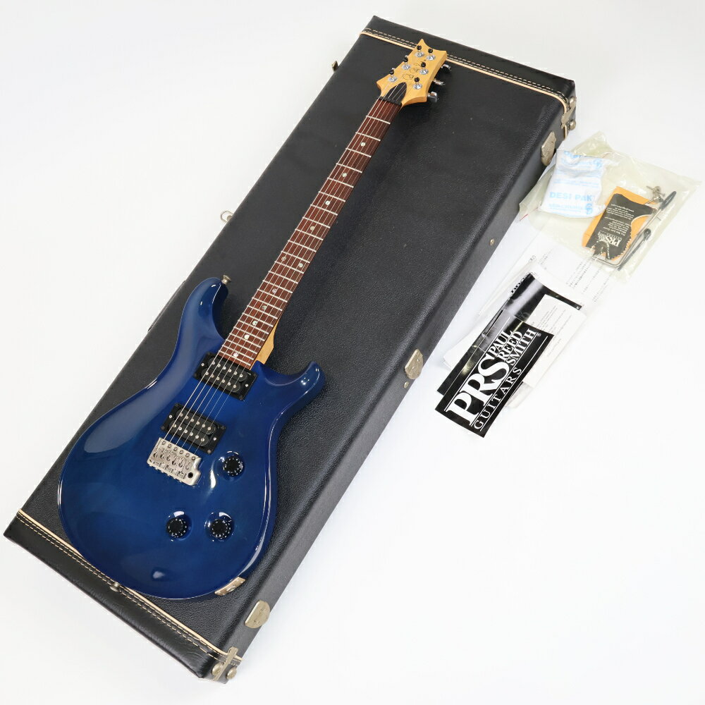 【中古】 エレキギター PRS CE 24 Mahogany Royal Blue 2005年製 20th Anniversary Wide Thin Neck Paul Reed Smith ポールリードスミスPRS CE 24 Mahogany Royal Blue の中古品です。中古なりのコンディションです。商品内容：本体・ハードケース・トレモロアーム・ネック調整レンチ・予備ロックペグキャップ・バードタグ他書類PRS CE 24 Mahogany Royal Blue中古です。バードタグ（チェックシート）の日付は2005年。PRSの20周年にあたる年なのでトラスロッドカバーには20thのロゴが入っています。シリアルの頭が6のため、出荷は2006年になってからされた可能性が高いです。ストラップピンはDunlopのロックピンに交換されています。CEは classic electricを意味し、メイプルネックをボルトオンジョイントした、いわゆるFスタイルのギターとしてPRSの初期からラインナップに加わっていました。2008年を最後に一旦レギュラーラインナップからは姿を消し2016年ごろに復活し、現在まで続くロングセラーモデルです。初期の仕様である HFS & Vintage Bassピックアップ搭載。ネックはWide Thin。近年のPRSでは最も本数の多いPattern Thinに近いシェイプです。その名の通りやや薄めではありますが貧弱な感じはなく、やや幅広なことからテクニカルなプレイヤーにも好まれます。メイプルトップの多いCEですが本機はオールマホガニーボディー。深みあるのロイヤルブルーからにうっすらとマホの木目が確認できます。ロックタイプのペグ、PRSトレモロブリッジなどピックアップを含めハードウェアはCutom系と比べても遜色はなく、Customとは違うもう一つのPRSの本流として存在し続ける1本です。スイッチは初期PRSではお馴染みの5WAYロータリースイッチ。内側コイル同士のハーフトーン、外側コイル同士のハーフトーンなどそれぞれ個性的で「使える」5種類のトーンを操作できます。小傷、パーツのくすみなど使用感のある中古らしいコンディションですが極端に大きなダメージはありません。ピックアップ周辺うっすらと弾き傷あり。ブリッジパーツにくすみ、軽微な腐食あり。稼働部の動きに問題なし。ボディー全体にペン先大、米粒大の打痕、それに伴う白濁、薄い引っ掻き傷、擦り傷あり。その他演奏に伴う細かな傷や軽微な汚れがございます。フレットは局所的な凹みはなく、全体で9割程度の残り。トラスロッドは締方向、緩め方向ともに稼働幅があります。動作確認済み。出力、コントロール共に問題ありません。重量約4.08kgハードケースが付属します。Body: MahoganyNeck: MapleFingerBoard:RosewoodNeck Carve: Wide Thin, 24-fret, 25” scale lengthInlays: MoonTuners: PRS-designed locking tunersBridge: PRS-designed tremoloPickups: HFS & Vintage BassElectronics: volume, tone, 5-way Roatary