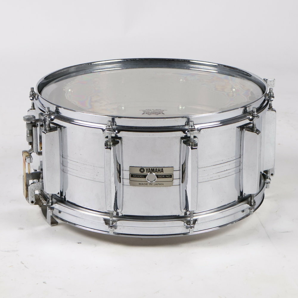 【中古】 スネアドラム ヤマハ YAMAHA SD-965M Seamless Steel Shell 14x6.5 Made in JapanYAMAHA SD-965M Seamless Steel Shell 14x6.5 の中古品です。中古なりのコンディションです。商品内容：本体のみシェルやフープ、ラグ、ストレイナー部等全体的にビッツ（点状のメッキの浮き）があります。全体的にかなり使用感のあるコンディションです。1980年代中頃に発売されていたシームレススティールシェルの国産スネアドラムです。継ぎ目の無い（シームレス）スチールシェルとスナッピー全面当たりスナッピーを採用しており、鋭く抜け感のあるアタックが特徴です。サイズ：14×6.5シェル：シームレス スチールテンション：10テンションMade in Japan 日本製