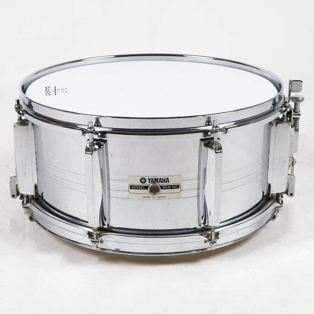 【中古】 スネアドラム ヤマハ YAMAHA SD765M Seamless Steel Shell 14x6.5 Made in JapanYAMAHA SD-765M Steel Shell 14x6.5 の中古品です。使用感のあるコンディションです。商品内容：本体のみ各所にくすみ、サビ、メッキの劣化などが見られます。1970年代後半から1980年代にかけて発売されていたシームレススティールシェルの国産スネアドラムです。継ぎ目の無い（シームレス）スチールシェルとスナッピー全面当たりスナッピーを採用しており、鋭く抜け感のあるアタックが特徴です。内蔵ミュートあり。サイズ：14×6.5シェル：シームレス スチールテンション：8テンションMade in Japan 日本製