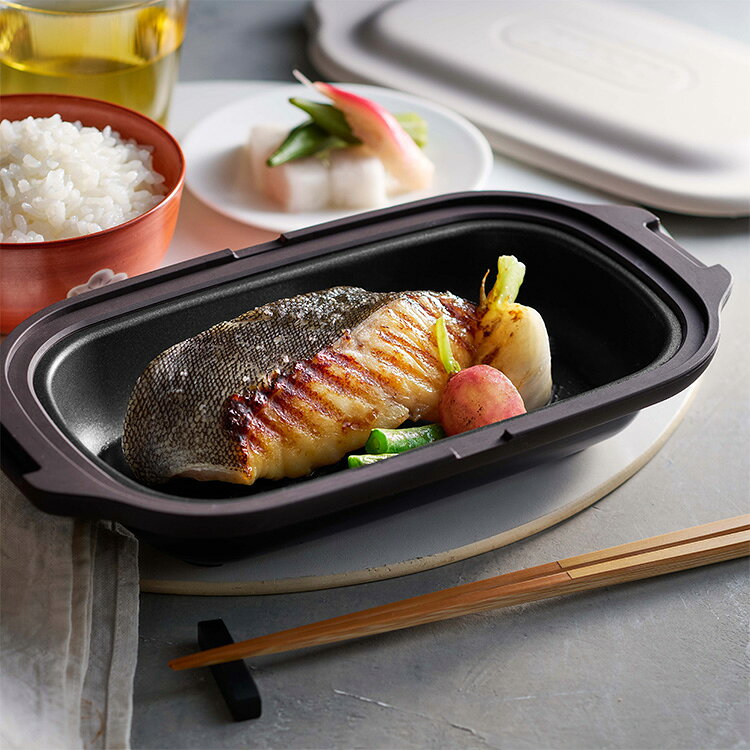 DETAILS / 商品詳細 電子レンジに入れるだけ！焼く・炒める・蒸す・煮る・温め直すの1台5役！グリルのような焼き目がつく波型プレートは、余分な脂も落ちてヘルシー！付属のシリコーン鍋敷きに置いて、温かいまま食卓へ♪ 商品サイズ 本体：約幅230×奥行125×高さ50（mm） プレート内寸：幅175×奥行95×高さ25（mm） 材質 プレート：アルミメッキ鋼板（内面：ふっ素樹脂塗膜加工、外面：焼付け塗装） 蓋：アルミメッキ鋼板（内面：ふっ素樹脂塗膜加工） プレートリング・蓋カバー：シリコーンゴム シリコーン鍋敷き：シリコーンゴム 重量 約415（g）（付属品含まず） カラー ペールアクア / グレージュ 仕様 満水容量：420mL 対応熱源：電子レンジ 耐熱温度：シリコーンゴム 250℃ 付属品：シリコーン鍋敷き、レシピブック、ユーザーズガイド 備考 お買い物の際の注意事項は、会社概要の「その他の注意点」を必ずご確認ください。 注意事項 ※対応していない使い方：直火、ガスコンロ、電磁（IH）調理器、電熱調理器、ハロゲン調理器、オーブン、冷蔵、冷凍ではご使用できません。