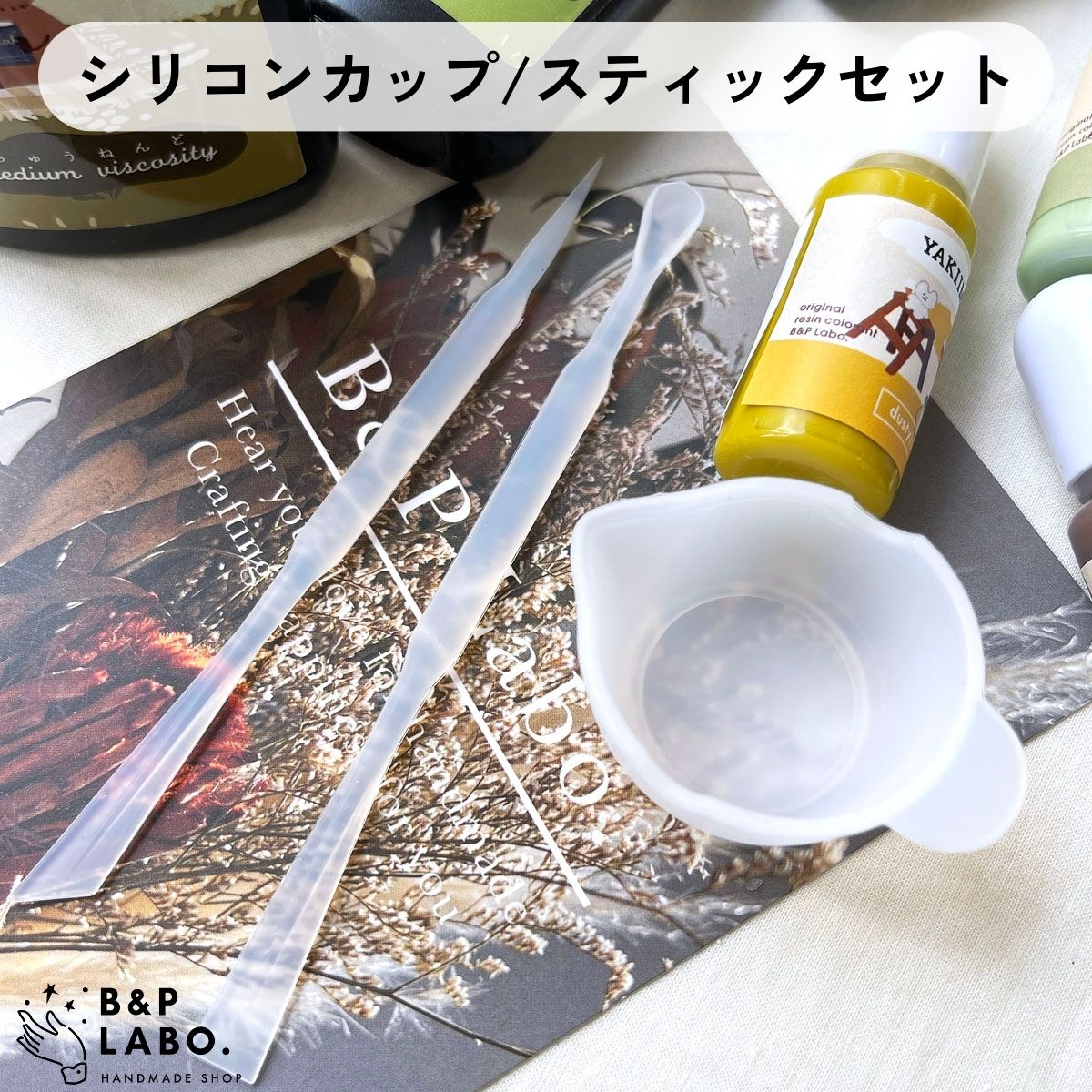 シリコン製の調色カップとスティック 2種の レジンワークに欠かせない3アイテムがセットで登場!! 注ぎ口のついたカップは モールドへの流し込み時に重宝します◎ シリコン製で柔らかいので ご使用後は残ったレジンをライトで硬化して お手入れも簡単に♪ 【サイズ】 カップ:直径約38mm/深さ約24mm スティック全長120mm 【材質】シリコン 【入数】 カップ1ヶ・スプーン型スティック1本 シャープ型スティック1本入【関連キーワード】ポスト投函 国内発送 ネコポス メール便 簡易包装 uvランプ ワークショップ カシャカシャ シェイカーレジン シェイカーモールド セルフネイル ナチュラル レディース ニュアンス 女 女性