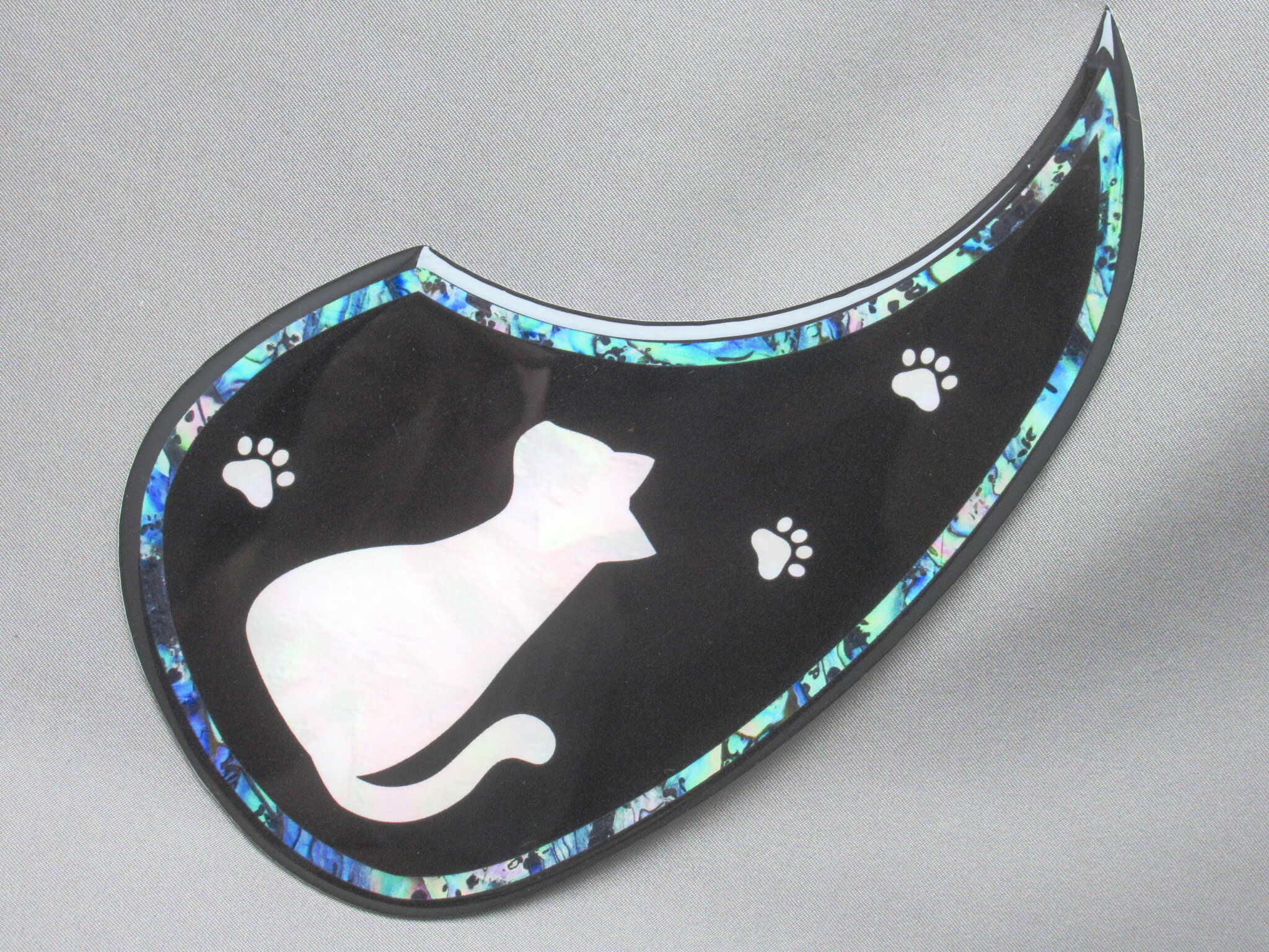 一般的なDサイズのピックガードに柄の入ったものは以前からありましたが、それらと一番違うのはこの品は柄の上に透明な膜があるということです。 ということは、弾きキズなどで柄が落ちていくということはありません。 本品の厚みは2.3mmあるので一般的な0.5mm厚のピックガードより5倍近い厚みがあります。 また、膜がR加工されているので厚さと相まって高級感があります。 なお、外周の枠や絵柄が貝のように見えますがそれっぽく見せているフェイクです。 それでも見るからにフェイクという出来でもなく、厚めの透明な膜のおかげだと思いますが柄などは意外と本物っぽく見えてなかなかの仕上がりになっていると思います。 もう少し安価なものをお望みの場合は0.5mm厚のタイプもございます。 この商品の普通郵便をご希望の方は下記注意点をご覧ください。普通郵便発送希望の方は注文時の画面の発送方法を普通郵便に変更しないと普通郵便に変更されませんのでご注意ください。