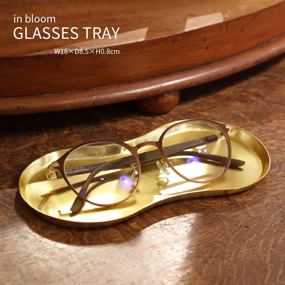 Item Spec 品　名in bloom GLASSES TRAY インブルーム メガネトレイ 特　徴 使いやすさやサイズにこだわったメガネトレイ。 1点1点ハンドメイドの繊細なデザインが特徴です。 光沢のあるゴールド仕上げで、デスク周りを華やかにしてくれます。 鍵やメガネ入れにちょうどよいサイズ感で、アクセサリー入れにもぴったりのサイズ感。 いずれも玄関・リビング・寝室や書斎などの必需品入れとしてもおすすめです。 サイズ約W18×D8.5×H0.8cm 材　質アイアン 生産国インド 備　考※1点1点手作りの商品のため、商品に若干の 　個体差があります。 ※若干の傷、溶接跡、塗装ムラのある商品が 　含まれます。 ※コーティング加工の際に、つり下げ式で 　行うためのつり下げ穴がございます。 　予めご了承くださいませ。 ※ハンドメイド製品の風合いを生かした商品 　のため刻印のムラなどがあります。 ※在庫が確保できない場合がございます。 　ご注文後メールにてご連絡いたします。 キーワードトレー アイアン 真鍮風 小皿 小物入れ キャッシュトレー プレート 北欧 アンティーク レトロ ナチュラル シンプル おしゃれ かわいい アクセサリー入れ メガネ コイン ピアス ペン ステーショナリー 玄関 リビング ダイニング カウンター 寝室 書斎 店舗 ショップ 什器 ギフト プレゼント 北欧雑貨アンティークゴールドに輝くトレイ アイアンで作られた真鍮風のトレイ。 真鍮そのものではありませんが、真鍮と同じく味わいのあるヴィンテージ感も演出しています。 メガネはもちろん、カギやアクセサリーなどを入れるトレイとして、北欧レトロな空間作りにも使いやすいアイテムです。 いろんな使い方にちょうどいいサイズ感 お出かけ前やお帰りの際にちょっと物を置いておく場所として、リビングや玄関先でカギやアクセサリーなどを置くのにちょうどいいアイテムです。 デスク周りをかわいくおしゃれに 書斎やリビングに置いているデスクの上で、散らかりがちなペンやクリップなどをすっきりさせるステーショナリーグッズとしてもおしゃれにかわいく活躍します。 アクセサリーの置き場所に リビングやドレッサーなどでは、時計、リングやピアスを外して置いておくのにもぴったりです。 ポケットの中のコインを入れたりと重宝します。 アンティークゴールドの味わい深い輝きのある真鍮に似せて、ハンドメイドでひとつずつ作られております。 ハンドメイドの魅力 ハンドメイドでひとつずつ作られており、アンティークゴールドの味わい深い輝きが魅力。 それゆえに、個体差もあれば、小さなキズもありますが、それを真鍮ならではの個性として素材本来の特性としてお楽しみください。 経年変化を楽しむ 人の指紋がついたり、少し黒ずんできたり。 触れるたび、使うたびに少しずつ色あいや輝き方が変化し、あなたとともに時間を過ごすことができる素材。 味わいのある風合いに仕上げていくという楽しみもあります。