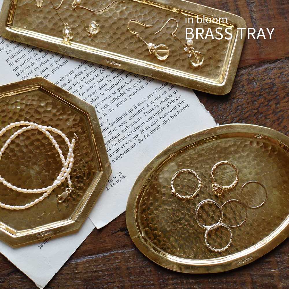 Item Spec 品　名in bloom BRASS TRAY インブルーム ブラストレイ 特　徴 アクセサリーや小物の収納・ディスプレイに使える真鍮製トレイ。 風合いあふれる鎚目(つちめ)模様を施したトレイでオーバル、オクタゴン、ロングの3タイプからお好みの形をお選びいただけます。 サイズオーバル：約 W13.5×D9.5×H0.4cm オクタゴン：約 W11×D11×H0.4cm ロング：約 W17×D5.5×H0.4cm 重　量オーバル：約 65g オクタゴン：約 58g ロング：約 40g 材　質真鍮 生産国インド 備　考※無塗装仕上げのため、黒くくすんできます。 　経年変化をお楽しみください。 ※真鍮は柔らかく変形しやすいため 　歪みがある商品がある場合があります。 ※ハンドメイド製品の風合いを生かした商品の 　ため刻印のムラなどがあります。 ※ワイヤーの端がとがっているため手を傷つけ 　る恐れがあります。 　飾り付ける際、取り扱いにご注意ください。 ※オーナメントの端が尖っている箇所があり 　ます。 　手や目を傷つけないようにご注意ください。 ※小さなお子様の手の届かないところでご使用 　ください。 ※在庫が確保できない場合がございます。 　ご注文後メールにてご連絡いたします。 関連キーワード北欧 北欧雑貨 真鍮 ブラス 槌目ハンマートーン トレイ トレー コイントレー 楕円形 オーバル 八角形 オクタゴン 風水 長方形 四角 おしゃれ かわいい アクセサリー ジュエリー ピアス ネックスレス 指輪 小物置き 小物入れ 収納 玄関収納 キートレー 鍵 ちょい置き メガネ 時計 シンプル ナチュラル アンティーク レトロ カフェ 店舗什器 ゴールド プレゼント ギフト 誕生日 一人暮らしアンティークゴールドに輝くトレイ アクセサリーや小物の収納・ディスプレイに使える真鍮製トレイ。 風合いあふれる鎚目(つちめ)模様を施したトレイです。 ブラストレイはオーバル、オクタゴン、ロングの3タイプからお好みの形をお選びいただけます。 個性が光るハンマートーン ハンマートーンは、槌目（つちめ）加工と言われ、板材にハンマーを丁寧に打ちつけ、その風合いを楽しむ伝統的な技法をいいます。 無機質な金属に、小さな連続する波が打ったような有機的な表情をプラスしてくれます。 インテリアに小さな個性をプラスしてくれる存在になってくれそう。 オーバル 楕円形のオーバルタイプは、W13.5×D9.5×H0.4cm。 アクセサリートレイの他、キートレイにしたり幅広くお使いいただけます。 人の指紋がついたり、少し黒ずんできたり。 触れるたび、使うたびに少しずつ色あいや輝き方が変化し、あなたとともに時間を過ごすことができる素材です。 味わいのある風合いに仕上げていくという楽しみもあります。 オクタゴン 八角形のオクタゴンタイプは、約 W11×D11×H0.4cm。 アクセサリートレイの他、キートレイや クリップ、付箋などデスク周りで使う小物トレイにもおすすめです。 形の違うトレイを組み合わせることで、さらに可愛く、おしゃれにコーディネートしていただけます。 ロング 長方形のロングタイプは、W17×D5.5×H0.4cm。 アクセサリートレイの他、ペンやクリップなど デスク周りで使う文房具トレイにもおすすめです。 ハンドメイドでひとつずつ作られております。 それゆえに、個体差もあれば、小さなキズもありますが、それを真鍮ならではの個性として素材本来の特性としてお楽しみください。