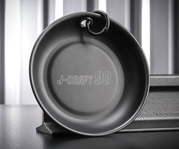 「黒で魅せる、現場で使える。ビス・ナットを逃がさないJ-CRAFT99のマグネットトレイ」 ロブテックスのフラッグシップ「J-CRAFT99（ツーナインズ）」に、2026年8月21日発売の新商品「マグネットトレイ」が加わりました。 取り外したビス・ナットや小物部品を強力マグネットで吸着し、作業中の部品紛失を防ぐ丸形トレイです。 側面のカラビナ用穴には「ハトメ加工」を施し、付属のカラビナリングで腰袋やベルトループから吊り下げて携行できます。 表面は傷や塗装剥がれに強い「フッ素樹脂コーティング」、本体は耐食性に優れたステンレス製で、屋内外を問わず長く使えます。 ゴムカバーには高級感のあるシボ加工とJ-CRAFT99ロゴを配した、所有する歓びまで設計されたJ-CRAFT99仕様です。 開発のこだわり 市販のマグネットトレイは自動車整備向けの製品が中心ですが、本製品はエアコン工事や電気工事など「腰に吊って使う職人」の現場も想定して開発されました。 外したネジをその場でカチャッと吸着できるよう、設計段階から側面に吊り下げ用の穴を設け、穴の縁にはハトメを打っています。 穴をくり抜いただけのトレイはエッジでカラビナや手を傷つけやすく、塗装も剥がれやすいのですが、ハトメ加工なら引っかかりがなく安全に使えます。 トレイ表面にはフッ素樹脂コーティングを採用し、ネジやボルトを置いても傷が入りにくく、同じ黒でも塗装が剥げにくいのが違いです。 フッ素樹脂加工はマグネット部の接着が難しく、素材に合う接着剤の選定や工程の見直しで発売時期を遅らせてでも完成度を優先しました。 「見た目の高級感」と「現場での実用性」を妥協なく両立させた、価格差以上の価値がある一品です。 特長 ビス・ナットの一時保管や作業中の部品紛失防止に最適です。 強力マグネット採用で、ボルトやナットなどの鉄製小物をしっかり吸着します。 強力な磁力により、トレイ本体も鉄製の工具箱や棚・壁面にガッチリ固定できます。 側面穴にはハトメ加工を施し、カラビナ装着部の耐久性と安全性を高めています。 付属のカラビナリングで腰袋やベルトループから吊り下げ可能です。 お持ちのカラビナをつなげると皿が正面を向き、さらに使いやすくなります。 耐食性に優れたステンレス製（SUS430）で、屋内外の使用環境に対応します。 フッ素樹脂コーティングにより、キズがつきにくく塗装も剥がれにくい仕上げです。 油汚れも落としやすく、お手入れが簡単です。 ゴムカバーは高級感のあるシボ加工＋J-CRAFT99ロゴ入りのオリジナルデザインです。 用途に応じて選べる2サイズ展開（φ108mm・φ150mm）です。 用途 エアコン工事・電気工事・設備工事でのビス・ナットの一時保管に。 自動車・バイク整備でのボルト・ナットの整理、紛失防止に。 鉄製工具箱や作業台、壁面に固定してのパーツ管理に。 仕様 品番JBMGC105JANコード4963202016360メーカーLOBSTER(ロブテックス)シリーズJ-CRAFT99(ツーナインズ)直径φ108mm高さ28mm皿深さ17mmマグネット部径φ63mm磁石種類フェライト磁石トレイ部材質ステンレス SUS430トレイ部表面処理フッ素樹脂加工 ブラックメタリックマット付属品カラビナリング φ24mm（出荷時本体装着済）重量180g発売日2026年8月21日 セット内容 マグネットトレイ本体（JBMGC105） カラビナリング φ24mm（出荷時本体装着済） ラインナップ サイズ違いの大サイズは品番 JBMGC150です。 同じ形状でLOBSTER（エビ印）ロゴ入りゴムカバーの通常品（品番 MGC105）もございます。 注意事項 商品をご使用になられる前に、商品に添付の取扱説明書をよくお読みいただき、正しくご使用ください。 改良のため仕様等を予告なく変更することがあります。 寸法等は公称値のため多少の数値の上下があります。 ブランド紹介 ロブテックス ツーナインズ（J-CRAFT99）は、品質に一切妥協せず「日本を代表する工具」を目指して生まれたJ-CRAFTの思想を受け継ぎながら、さらに「洗練」と「覚悟」を強めたプレミアムシリーズです。ブランド名に込められているのは、J＝「日本品質」、CRAFT＝「技巧・技術」、そして「現状に満足せず百（完璧）を追い求める姿勢」。この考え方を、製品の機能だけでなく、持ったときの高揚感まで含めて形にしています。作り手は、1888年（明治21年）創業、モンキレンチの国産化を成功させた老舗LOBSTER（エビ印）のロブテックス。130年を超えて磨かれてきたエビ印品質を土台に、高級感あるブラック基調の外観で、道具としての実用性と所有する歓びを両立させています。製品づくりの起点は、現場で働く職人の声。発売後も落下防止穴の位置ひとつまで見直して改良を重ねる、百（完璧）を追い続ける姿勢こそがこのシリーズの本質です。さらにJ-CRAFT99は「取扱い店舗限定商品」。安さを競うのではなく、価値が正しく伝わる売り場で、適正な価格のまま長く選ばれ続けること。その約束を守り抜くことで、ブランドの未来と日本のものづくりを育てていく考え方まで含めて設計されています。エヒメマシンは、このJ-CRAFT99に構想段階から関わり、2023年6月の誕生時にはWEB先行販売店としてブランドの立ち上げを担った、ゆかりの深い販売店です。現場の声をメーカーに届ける「架け橋」の役割を担い、商品写真は1点ごとに複数カットを重ね、肉眼で見た質感に近い画像づくりにこだわっています。「良いものを、価格を崩さず、大切に売る」という約束をブランドと共有しながら、日本の職人魂が詰まったロブテックスの原点回帰と挑戦を、これからも自信を持ってお届けします。 人気のカテゴリ 新商品 今月の特価品 オリジナル商品 ワケあり特価品