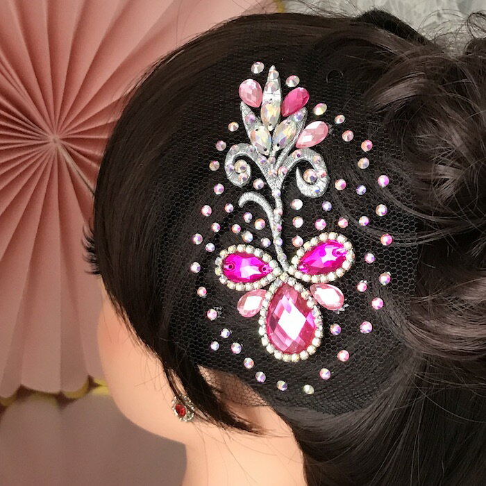 ラインストーン付きのヘアアクセサリーになります。 綺麗なストーンをアクセントとして散りばめ、 様々な色の輝きが放っていますので、 ドレスや衣装などに合わせやすいデザインになっています。 豪華でよく光りますので付けるだけで髪上げが栄えます。 競技会、パーティー、イベント、社交ダンスの衣装にも合います。 取り付けはヘアスタイルをセットした後、 アメピンやUピンで固定してお使いください。 サイズ：H12cm W7cm（装飾部分のサイズ） カラー：ピンク・ABオーロラストーン チュール部分は、 ご自身のヘアスタイルやお好みに合わせて カットをしてお使いいただいても大丈夫です。 ※当店オリジナルデザインのハンドメイドです。