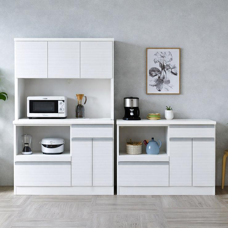 ■商品番号：341896 【この商品のスペック】 ■寸法 ・90キッチンボード 　幅89.9cm×奥行44.5cm×高さ180cm ・120キッチンボード 　幅118.9cm×奥行44.5cm×高さ180cm ・90カウンター 　幅89.9cm×奥行44.5cm×高さ87cm ・120カウンター 　幅118.9cm×奥行44.5cm×高さ87cm ■梱包サイズ ・90キッチンボード(2個口) 　(1)幅92cm×奥行47cm×高さ102cm 　(2)幅92cm×奥行47cm×高さ82cm ・120キッチンボード(2個口) 　(1)幅122cm×奥行47cm×高さ102cm 　(2)幅122cm×奥行47cm×高さ82cm ・90カウンター(1個口) 　幅92cm×奥行47cm×高さ87cm ・120カウンター(1個口) 　幅122cm×奥行47cm×高さ87cm ■素材 表面材：ハイグロスシート 棚板：上扉各1枚、下扉2枚 OP部天板・カウンター天板：ポリ合板 上台・下台OP上部：モイス付き 備考：コンセント・ゴムコーダー付き、フルオープンレール仕様（下段大引き出し） 上棚・下段：約8kg、棚板約5kg カウンター天板部分：約20kg 中央右スライド引き出し：約10kg 左下開き扉：下段約10kg、棚板約5kg 右下引出し：約15kg ■商品の特徴 シンプルで収納力抜群の 国産カップボード/カウンターシリーズです。 たっぷりまとめて収納できるスペース。 キッチンボードの上棚は 170cm と手の届きやすい高さです。 幅90cm/120cmのハイタイプ食器棚と カウンターの4タイプからお選びいただけます。 食器・調理家電・ 食品ストックまでしっかり収まる大容量設計で、 散らかりがちなキッチンもすっきりです。 天板を作業台として使えるので、調理や配膳も スムーズ。毎日の家事が効率よく進みます。 開き扉内部は6cm感覚の可動棚仕様です。 自由度が高いオープンスペースは 家電製品をおいたり作業スペースとしても便利(※キッチンボードのみ )。 下段の引き出しは高さに余裕があり、 大きな鍋やフライパンもすっきり収納可能。 重ね置きせずにしまえるため、 取り出しや片付けがスムーズです。 調理器具をまとめて収納でき、 キッチン全体が整った印象になります。 奥までしっかり引き出せる、フルオープンレールを採用。 奥までしっかり引き出すことができ、 ものの出し入れがスムーズです。 ※小引き出しは スライドレール仕様 ではありません。 家電製品を並べて置けるゆとりのある設計で、 電子レンジなど蒸気の出る家電にも対応。 背面には1500Wまで使用できる、 便利な2口コンセントを完備しています。 調理家電をその場で使えるため、 作業動線が整い、家事が効率よく進みます。 オープン部は便利なコンセント付き。 コード穴もついているので配線もスッキリ! ※90/120カウンターには2口コンセントは設置されていません 確かな仕上がりの日本製。組立の手間がかからないので 子育て世代にぴったり。組立が苦手な方や 時間に余裕がない方、作業が面倒な方などにおすすめ。 ■備考 ◎照明やモニターの発色の具合等によって、実際の商品と色味が異なる場合がございます。 ◎商品の個体差によりページ記載寸法と若干の差異が生じる場合があります。予めご了承ください。 ◎大型の完成品となります。事前に搬入経路が十分に確保出来るかのご確認をお願い致します。 日本製(大川家具)、完成品 [_kitchenmicrowave_][_kitchencounter_]バリエーションも豊富！カスタマイズも可能な当店人気No.1「ナポリ」シリーズはこちら／ ジャミル キッチンボードキッチン/カウンターシリーズ商品番号：341896 バリエーションも豊富！カスタマイズも可能な当店人気No.1「ナポリ」シリーズはこちら／