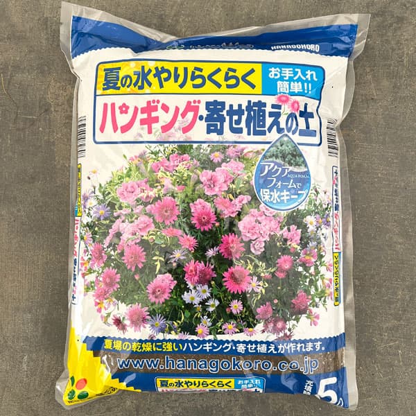 保水資材配合 水持ち効果を高めた培養土 吊鉢・鉢植えに 花ごころハンギング・寄せ植えの土5リットル入り水切れさせやすいハンギングバスケットや寄せ植え。「ハンギング・寄せ植えの土」は保水効果を高めた土なので水持ちがよく、夏の水やりラクラク　お手入れ簡単！保水効果が高く、軽量のアクアフォームを配合し、花付きを良くするリン酸成分が豊富に含まれています。主原料木質堆肥、ピートモス、ココナッツファイバー、アクアフォーム適応植物草花一般、コニファー類、カバープランツ一般、野菜苗内容量5リットル○特徴・保水効果が高く、軽量のアクアフォームを配合・花付きを良くするリン酸成分が豊富・根張りをよくする海藻成分を配合・ピートモスの保水効果をより高めるココナッツファイバーを配合○使用方法(草花、野菜の植え方)鉢底土を入れてから培養土を入れます。ポットから苗を外し、植え込んだら苗の周りに土を入れて完成。1袋5リットル入りです。※写真はイメージです。ハンギング・寄せ植えの土5リットル入りの栽培ガイド鉢に入る土の容量と植える苗の数