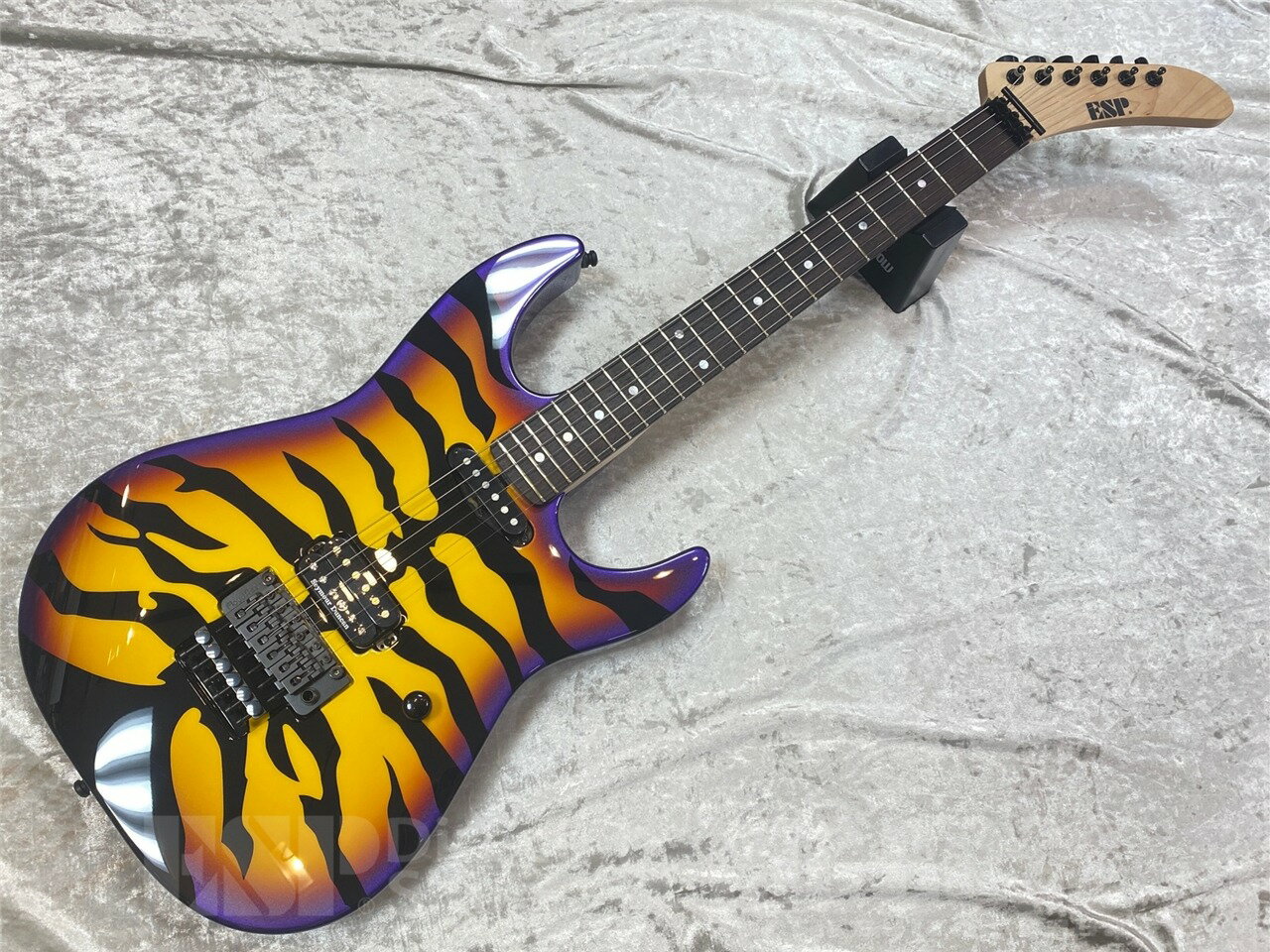 ■商品説明 鮮やかなタイガー柄が印象的な、ESPの“PURPLE TIGER”。 そのルックスだけでなく、こだわりのスペックが詰まった一本です。 ボディには、ESPの独自仕様であるヘヴィウェイト・ハードメイプルを採用。アルダーやアッシュにはない、タイトで輪郭のはっきりとした硬質なサウンドが特徴です。 最大のポイントは、ネックの独創的な設計。 ナット幅は一般的なエレキギターと同じ43mmのロックナット（R3）ですが、ネック自体の幅は45mmに設定されています。これにより、ローポジションではスムーズなフィンガリングを可能にしつつ、ハイポジションに行くほど指板にゆとりが生まれ、複雑な運指やチョーキング、ヴィブラートをより快適に行うことができます。 ブリッジピックアップには、世界的ギタリスト、ジョージ・リンチのシグネイチャーモデル、Seymour Duncan “The Hunter”を搭載。ハイパワーながらも明瞭なサウンドは、このギターのポテンシャルを最大限に引き出します。 ■主な仕様 BODY：Hard Maple NECK：Hard Maple GRIP SHAPE：GL Original U FINGERBOARD：Rosewood SCALE：648mm FRET：EXJ, 22 Frets NUT：Locknut (R3/43mm :45mm Neck Width) CONSTRUCTION：Bolt-on (246-Cut) TUNER：GOTOH SG360-07 BRIDGE：Floyd Rose PICKUPS：(Neck) ESP SS-120, (Bridge) Seymour Duncan Custom Shop ’78 CONTROL：Master Volume (w/ Push-Pull PU Select SW) COLOR：Purple Sunburst Tiger Graphic 重量:約5.0kg こちらの商品はESPクラフトハウス以外の店舗からの発送商品となります。 セットアップ・点検については、ESPクラフトハウス同様に行なっておりますのでご安心ください。 ※掲載商品は店舗/他のWEBサービス等と並行して販売しております。随時在庫状況の更新を行っておりますが、売り切れの場合はご了承下さい。 なお、在庫の確認につきましてはお電話・メールにてお問い合わせください。
