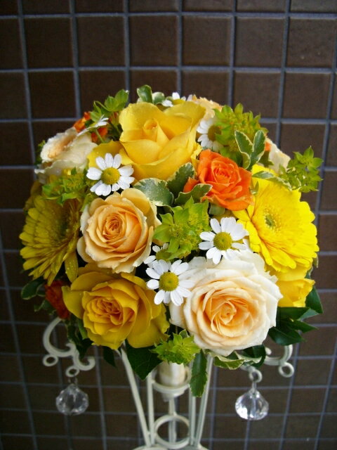黄色オレンジ系のバラに黄色のガーベラと小花等で アレンジ。かわいらしいブーケに仕上がっています。 直径約25cm。ブートニア付。　