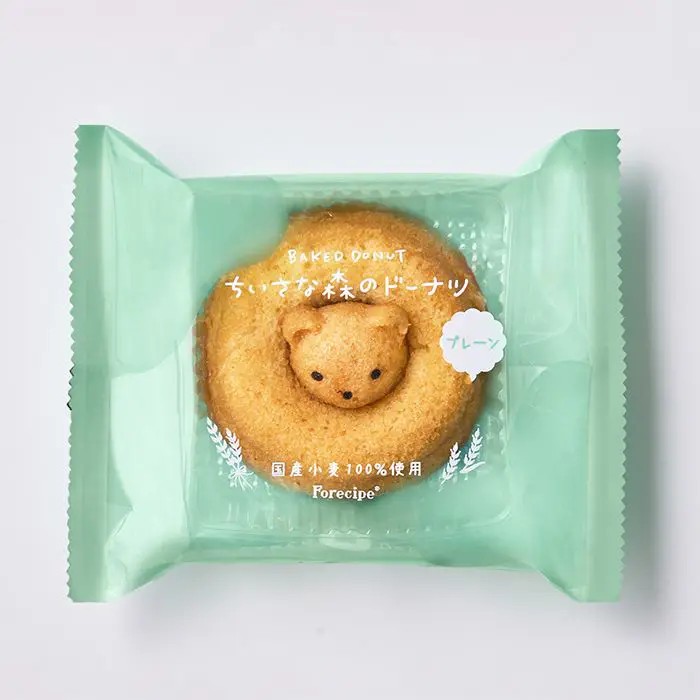 小さな森からくまがひょっこり。しっとり香ばしい、かわいい焼きドーナツドーナツの真ん中から、小さな森のくまがひょっこり顔をのぞかせる、愛らしい「ちいさな森のドーナツ くまプレーン」。 思わず笑顔になるかわいらしい姿は、見ているだけでも楽しい気分にさせてくれます。生地にはアーモンドプードルを練り込み、しっとりとした食感と香ばしい風味に焼き上げました。 ふんわりやさしい甘さの生地に、アーモンドのコクと香りがほどよく加わり、シンプルながらも味わい深い美味しさに仕上げています。食べてしまうのが惜しくなるほどのかわいらしさですが、ひと口味わえば、しっとりとした口当たりと香ばしい味わいに、もうひとつ食べたくなる美味しさ。 お子さまのおやつにはもちろん、大人のティータイムにもおすすめです。小さな森の物語を感じさせるような愛らしいドーナツは、毎日のおやつをちょっと特別な時間にしてくれる一品。 ご自宅用にはもちろん、かわいらしさを楽しめるプチギフトにもぴったりです。■内容量：1個■アレルギー：卵・乳・小麦■保存方法：常温■賞味期限：お届け時点で50日以上■サイズ：140×115×35mm（パッケージサイズ）■JANコード：4542511366597※こちらの商品は単品商品となります。ラッピング、熨斗等は不可となりますのでご了承ください。