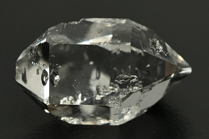 1.9×1.2×1.0cm　2.5g アメリカ・ニューヨーク州産のハーキマーダイヤの単結晶です。 非常に透明度が高く形も整った上質の結晶です。 ハーキマーダイヤは結晶の透明度が高く、強い輝きを放つことが特徴です。ダイアモンドの結晶に近い形状と輝きからハーキマーダイアモンドと呼ばれます。黒っぽいタール状の有機物が張り付いており、ハーキマー水晶の結晶内にはこれを内包しています。　