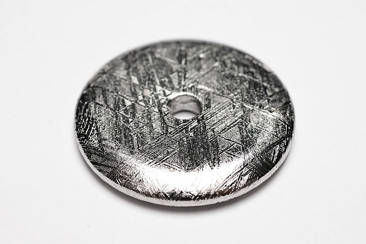 2.9×2.9×0.4cm 穴サイズ:約4mm 綺麗な格子模様が出ているギベオンのドーナツです。かなり大き目の穴が空いておりますので、革ヒモなどに通してペンダントトップとしてお使いいただけます。 表面は錆びにくいようにロジウムでコーティングされています。　