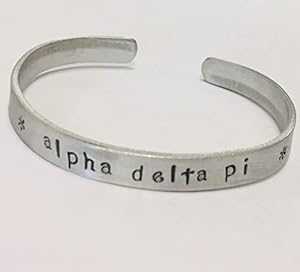 Alpha Delta Pi カフ ブレスレット - 変色しないアルミニウム製のカフに風変わりなフォントでハンドスタンプされており、正式にライセンスされています。 Ann Peden Jewelry Alpha Delta Pi Cuff Bracelet - handstamped in a whimsical font on a no Alpha Delta Pi カフ ブレスレット - 変色しないアルミニウム製のカフに風変わりなフォントでハンドスタンプされており、正式にライセンスされています。 Ann Peden Jewelry Alpha Delta Pi Cuff Bracelet - handstamped in a whimsical font on a no