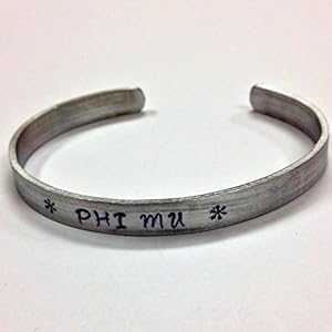 Phi Mu カフ ブレスレット - 変色しないアルミニウム製のカフに風変わりなフォントでハンドスタンプされており、正式にライセンスされています。 Ann Peden Jewelry Phi Mu Cuff Bracelet - handstamped in a whimsical font on a non tarnish alumin Phi Mu カフ ブレスレット - 変色しないアルミニウム製のカフに風変わりなフォントでハンドスタンプされており、正式にライセンスされています。 Ann Peden Jewelry Phi Mu Cuff Bracelet - handstamped in a whimsical font on a non tarnish alumin
