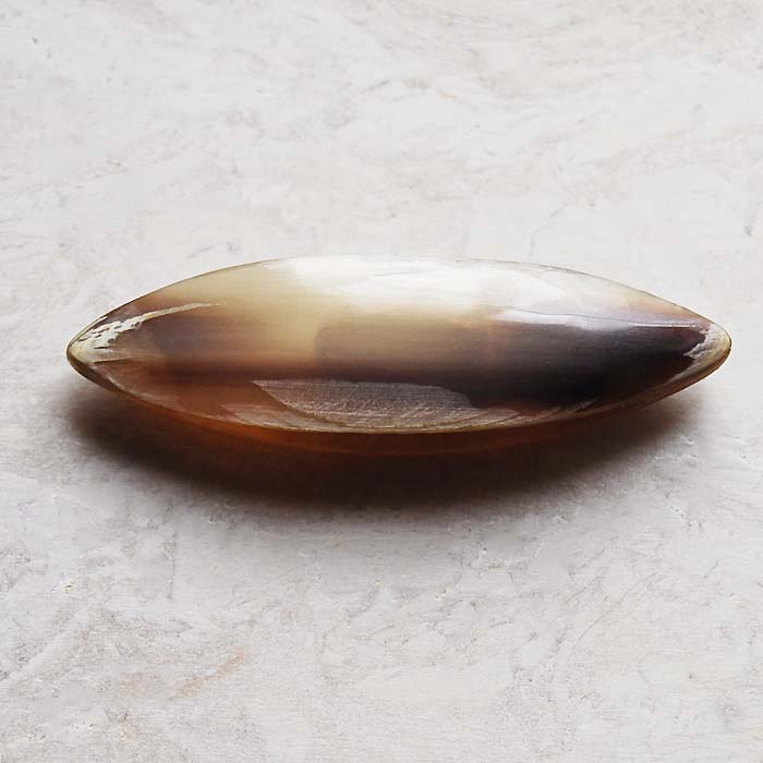 ホーン製のタティングシャトルです。 サイズ：長さ 6.0 cm 幅 1.9cm　厚み 1.1cm 色：グレーがかったあめ色にやや濃いグレーが差しています。白から黒までの色合いの半透明のまだら色で、細かいタッティングスレッド用にポイントが設定...