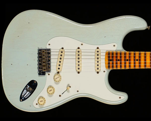 Description 1987年に設立され、最上級モデルを制作するために生まれたフェンダー・カスタム・ショップ（Fender Custom Shop）。マスタービルダーと呼ばれる巨匠達が製作を担当するマスタービルダー・シリーズやその他の多くのシリーズで厳選された木材選び、ピックアップのコイル巻きなど高い製作技術で作り上げられております。フェンダー社の長年の歴史と伝統が注ぎ込まれた世界中のミュージシャンから愛され続けるセクションです。 2022年の秋に行われたフォール・イベント（商談会）限定による特別なリミテッド・エディション「LTD 1956 STRATOCASTER JOURNEYMAN RELIC」のご紹介です。丸型だったストリングガイドが羽型に変更され、アッシュだったボディ材が白系統のブロンド・カラー以外、アルダー材へと変更された年である1956年ストラトキャスター。ボディには低～高音域までクセの無いサウンドをアウトプットする厳選された2ピース・アルダー、25.5インチ・スケールのネックと21フレット仕様の指板には硬めでクリアかつ歯切れの良いリフトソウン・メイプルを採用。ネックシェイプは1956年10月当時に採用されていたモデルを採寸した「10/56 "V"」を採用し、ラインナップの中でも最も太めで握り応えのあるシェイプですので、コシのある極太サウンドに貢献し、あらゆるプレイスタイルに最適な9.5Rの指板、フレットにはミディアム・ジャンボよりも少し幅が狭く高さのある「Narrow Tall」を採用するなどピッチの安定したスムーズなフィンガリングを可能にいたします。 ピックアップ・システムにはハンドワウンド（手巻き）によって丁寧に製作された「Masterbuilder Designed Tone Bone」を搭載し、ジョン・クルーズ氏によってデザインされたピックアップで、60年代初期ピックアップのターン数を控えめにし、出力が低めながらもゲインを加えた時のサスティーンはタイトで芯の強さも兼ね備えた張りのあるサウンドです。また配線の「Fat '50s」コントロール・アセンブリからは、より透明感のあるブルームで全体的に強いトーンを実現し、ボリュームとトーン・コントロールはよりスムーズで均一に反応することで、ボリュームを巻き戻した時に発生する典型的なトレブルロスを少なくしており、「1/2 blender」配線からは、セレクター・ポジション（1）と（2）の時、フロントPUがブレンドされることで多彩なサウンドバリエーションを実現。エイジング処理は2015年、新たに加わった「ジャーニーマン・レリック」を施し、『弾き込まれているが、粗末には扱われていない』といったコンディションの良いヴィンテージ・ギターを再現。ウェザーチェックと細かな打痕が入ったボディ、引き込むことによって生じる塗装剥がれを再現したネック・フィニッシュなどフェンダー・ファン待望の加工ではないでしょうか。そしてヘッド裏の『LIMITED EDITION』と入ったロゴ・デカール、『LIMITED EDITION』と刻印されたジョイント・プレートも見逃せないポイントです。ステージ映えは間違いなし、お薦めの限定ストラトキャスター・カスタムとなっております。 Specification Body Finish: Journeyman Lacquer Finish Body Material: 2-Piece Select Alder Body Bridge Pickup: Custom Shop Hand-wound Masterbuilder Designed Tone Bone Middle Pickup: Custom Shop Hand-wound Masterbuilder Designed Tone Bone Neck Pickup: Custom Shop Hand-wound Masterbuilder Designed Tone Bone Color: White Blonde Configuration: SSS Controls: 1 Volume, 1 Tone. 1/2 Blender Fingerboard Material: Maple Fingerboard Radius: 9.5" Radius Fret Size: Narrow Tall / 6105 Hardware Finish: Nickel Bridge: Custom Shop Vintage Synchronized Tremolo Neck Finish: Relic Lacquer Neck Material: Riff Sawn Maple Neck Shape: 10/56 "V" (.880-.980") Number of Frets: 21 Nut Material: Bone Nut Width: 1.65" (42 mm) Position Inlays: Dot Pickguard: 56 Strat Switching: 3-way Tuning Machines: Vintage-Style Tuning Machines Included Accessories: Tremolo Arm, Deluxe Hardshell Case; Certificate of Authenticity.