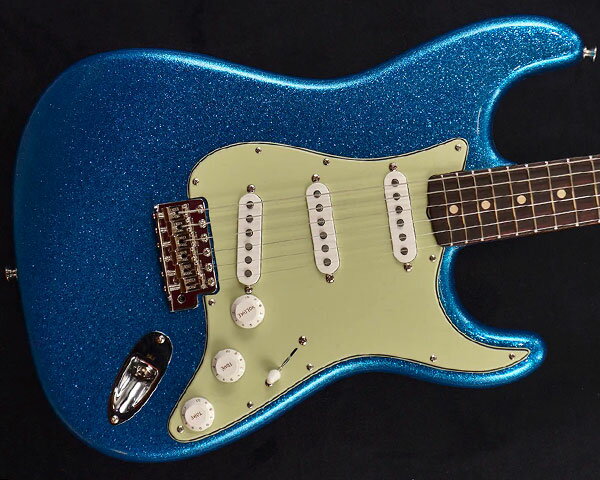 Description 1987年に設立され、最上級モデルを制作するために生まれたフェンダー・カスタム・ショップ（Fender Custom Shop）。マスタービルダーと呼ばれる巨匠達が製作を担当するマスタービルダー・シリーズやその他の多くのシリーズで厳選された木材選び、ピックアップのコイル巻きなど高い製作技術で作り上げられております。フェンダー社の長年の歴史と伝統が注ぎ込まれた世界中のミュージシャンから愛され続けるセクションです。 ディーラー・オーダーによるカタログ外モデル「1963 STRATOCASTER NOS」のご紹介です。ブルース・ギタリスト達から熱い支持を受ける1963年製ストラトキャスター。ボディには低～高音域までクセの無いアルダーをセレクトし、25.5インチ・スケールのネックには硬めでクリアかつ歯切れの良いメイプル材、21フレット仕様の指板には倍音豊かで優れたサスティーンを生むAAAグレードのローズウッドを採用。ネックシェイプはローポジションでは細く、ハイポジションにいくにつれ厚みのあるネックに仕上げた60年代中期の「Mid 60's Oval “C”」、あらゆるプレイスタイルに最適な9.5Rの指板、フレットにはジャンボ（6100）より高さをやや低くした「Medium Jumbo」を採用するなど演奏性は快適です。 ピックアップ・システムにはハンドワウンド（手巻き）によって丁寧に製作された「1960 Strat」を搭載し、綿密な測定に基づき、設計された「60s Strarocaster Single-Coil」を搭載し、繊細でクリアな表現力を持ち、タイトで芯の強さをも兼ね備えた張りのあるサウンドです。エイジング処理は加工を施さない新品当時を再現したNOS（New Old Stock）を施し、さらに弾き込むことで豊かな鳴りとヴィンテージライクなサウンドへと成長していく1本。お薦めのストラトキャスターとなっております。 Specification Blue Sparkle Alder Body Mid 60’s Oval C Shaped Maple Neck 9.5″ Radius AAA Rosewood Fingerboard Medium Jumbo Frets Handwound '60 Relic Strat Pickups Hardshell Case