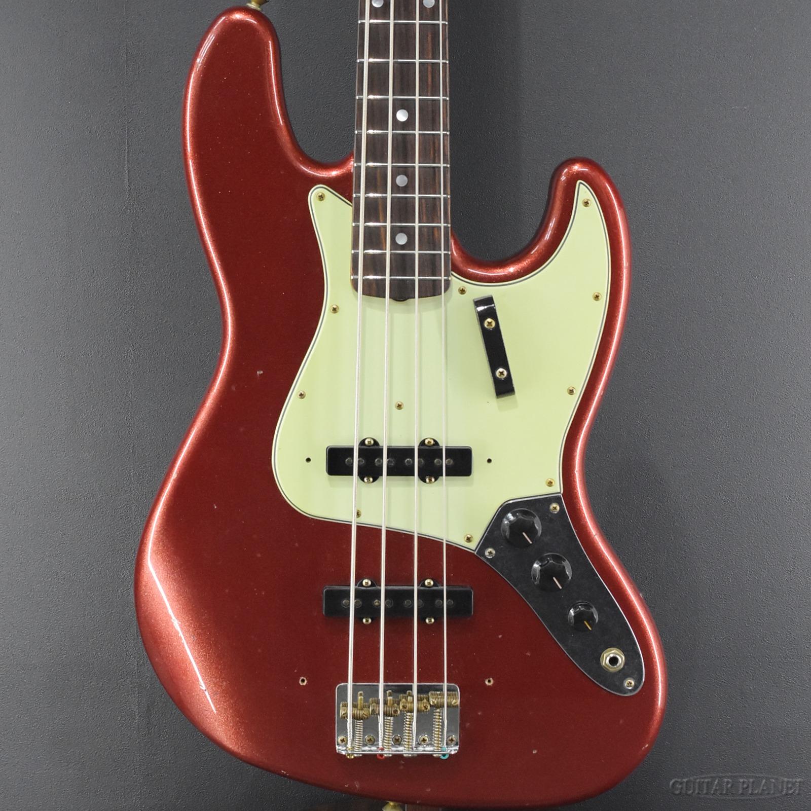 2025年のカタログモデルとなる「1965 Jazz Bass Journeyman Relic」を基にして、弊店ならではのオーダーを行った1本。 アルダー2ピースのボディとしてネックには柾目(クォーターソウン)のメイプルを採用。1960"U"のネックグリップを採用しながらも、ローポジションは握り応えのある僅かに厚いグリップ。ハイポジションは逆に薄くすることでローポジションからハイポジションにかけて厚みの差が少なくなるグリップを再現しています。 指板はローズウッドのラウンド貼りとなり、1965年モデルでは本来パーロイドのドット・ポジションマークとなりますが、高級感のあるマザー・オブ・パール(白蝶貝)のドット・ポジションマークを配しています。細かい点ですが、サイドのポジションマークも贅沢にマザー・オブ・パールを使用しています。 指板ラジアスは7.25インチ、フレットはヴィンテージタイプのフレットで、ヴィンテージ・スペックのネック周りを意識しています。 ピックアップにはハンドワウンドのVintage J-Bassを2基マウントし、2ボリューム、マスタートーンの定番ともいえる3ノブのコントロールになります。 ジャズベースらしいクリアでシャープなサウンドを持つ個体。高音域の音抜けに優れておりアタック感が際立つ1本です。 ラメ感の強いファイヤーミスト・レッドのカラーリングは、ラメ感がありながらも赤系のキャンディ・アップル・レッドとは一味違う落ち着きある印象です。 是非この機会にご検討ください。 SPEC Body:Alder Neck:QTR-Sawn Maple Neck Shape:60 J-BASS"U" Neck Scale:34" Fingerboard:AAA Rosewood(Round Lam),7.25"R Number of Fret:20,Vintage Pickups:Hand-Wound Vintaage J-Bass Control:2Volume,Tone Case:Black Tolex Hard Case /_/_/_/♪出荷前調整のご要望承ります♪_/_/_/_/ ギタープラネットではご注文頂いた商品は 新品中古問わず検品・調整してから出荷致します。 弦高などの細かなセッティング等、お好みに 合わせての調整も可能ですので、お気兼ねなく お申し付けくださいませ。 /_/_/_/_/_/_/_/_/_/_/_/_/_/_/_/_/_/_/_/_/_/_ お問い合わせフリーダイヤル：0120-37-9630　